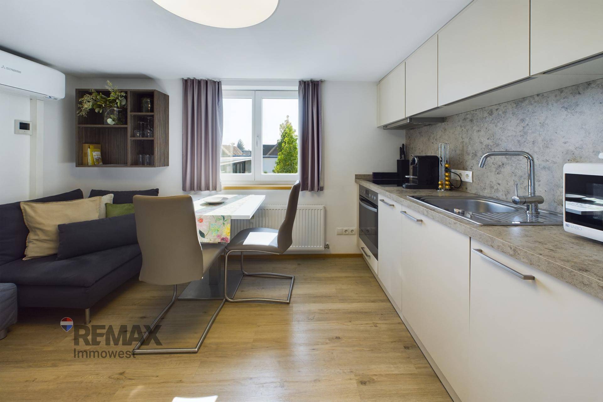 Moderne Küchenzeile mit Essbereich und angrenzendem Sofa in hellem Ambiente.