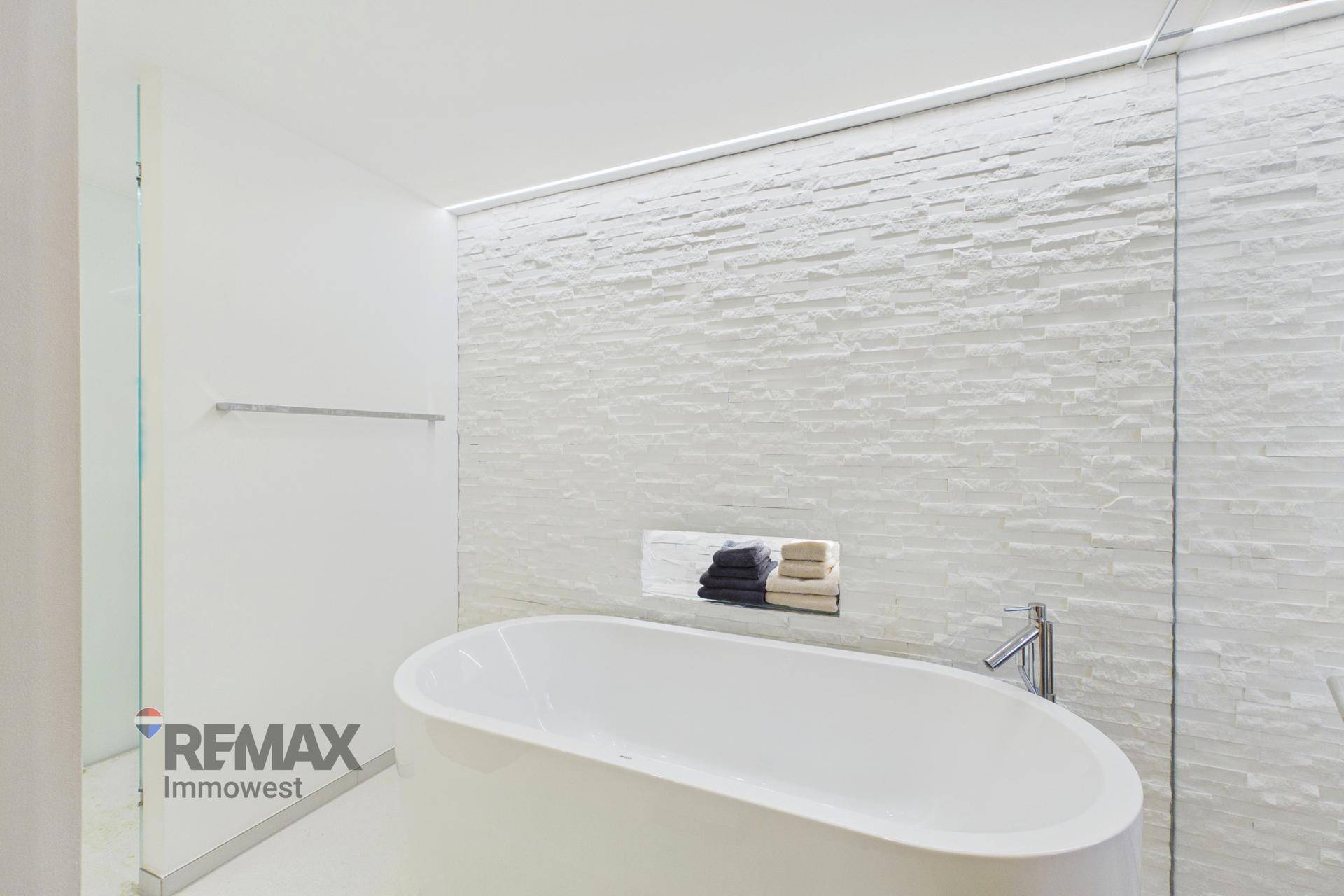 Modernes Badezimmer mit freistehender Badewanne und strukturierter weißer Wand.