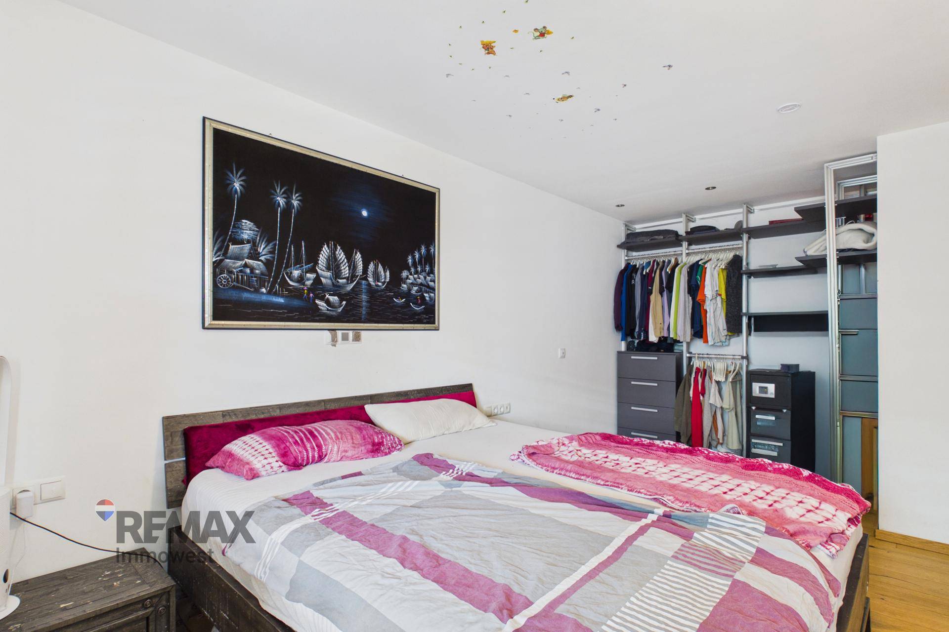 Schlafzimmer mit Doppelbett und offenem begehbarem Kleiderschrank-System.