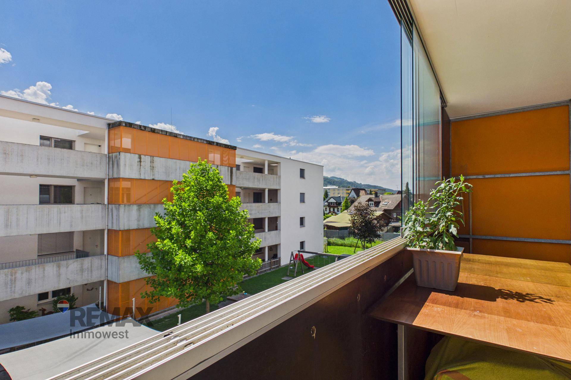 Balkon mit Blick auf einen Spielplatz und die umliegenden Wohngebäude.