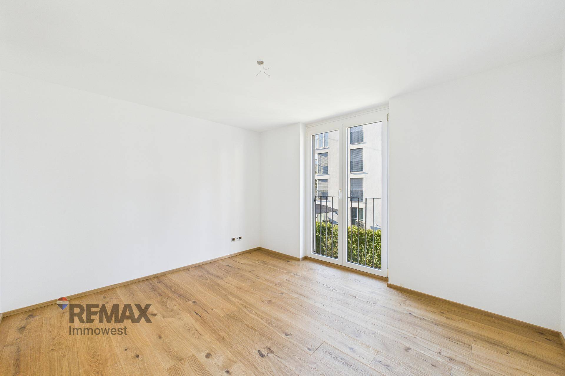 Helles Zimmer mit Parkettboden und Zugang zu einem französischen Balkon, ideal als Schlafzimmer.