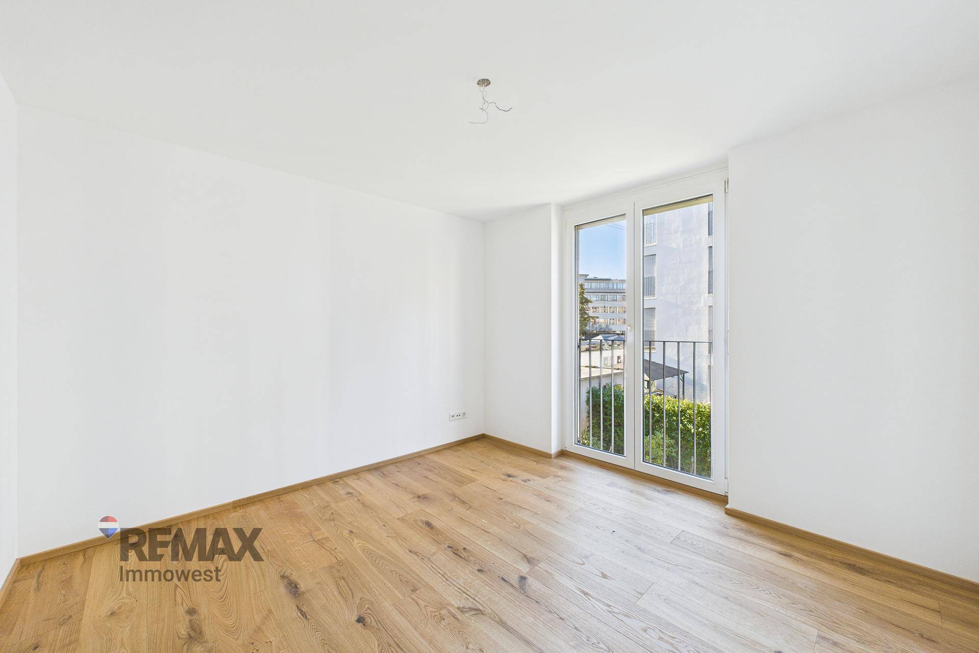 Lichtdurchflutetes Zimmer mit Parkettboden und französischem Balkon, bietet viel Tageslicht.