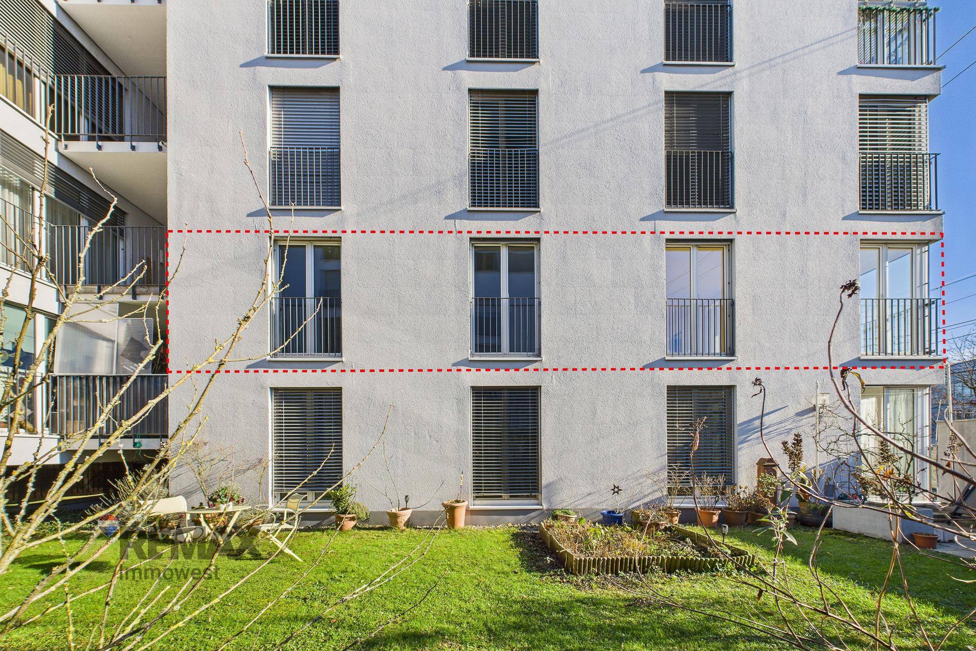 Fassade des Gebäudes mit französischen Balkonen und einem kleinen Gartenbereich im Erdgeschoss.