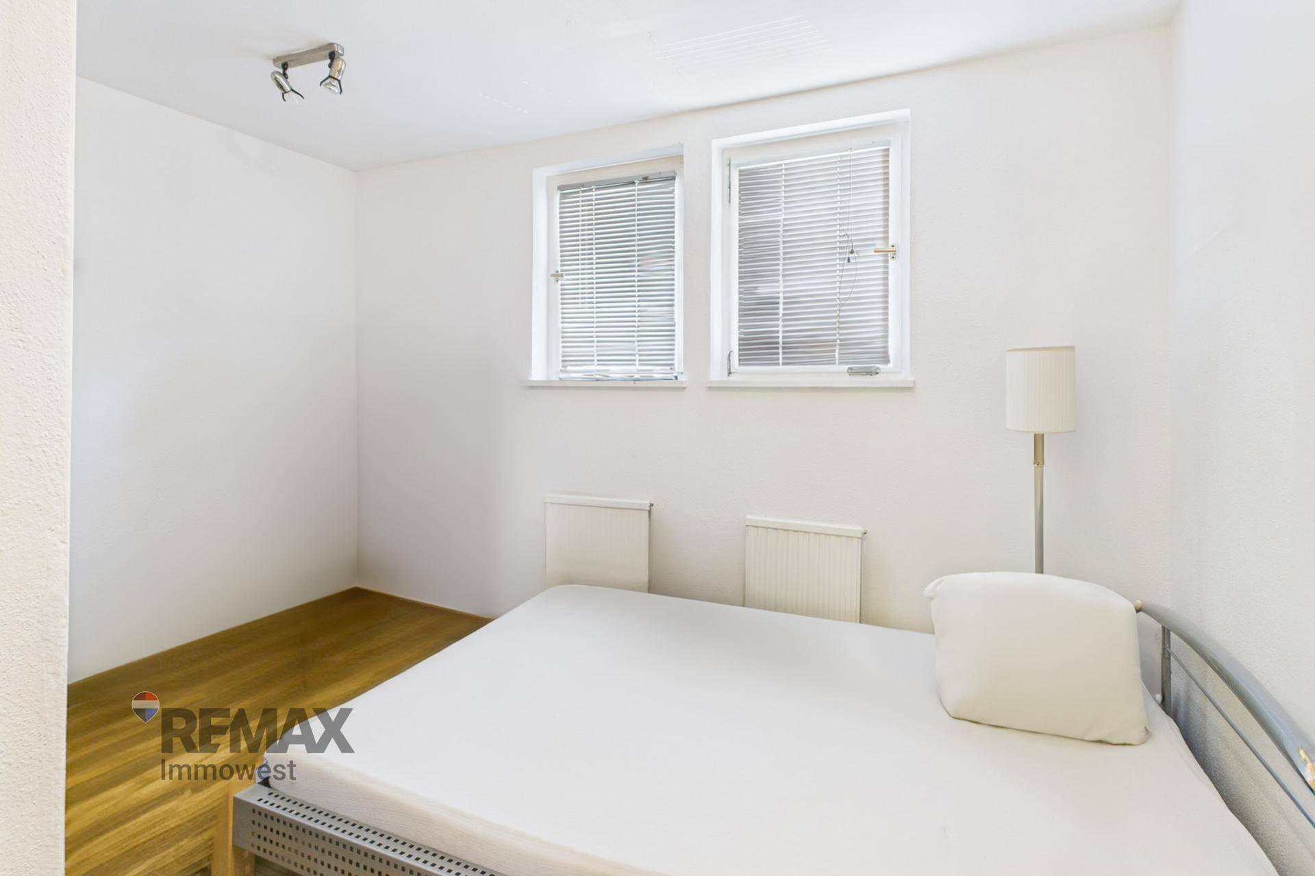 Helles Schlafzimmer mit Holzboden und zwei Fenstern für viel Tageslicht.