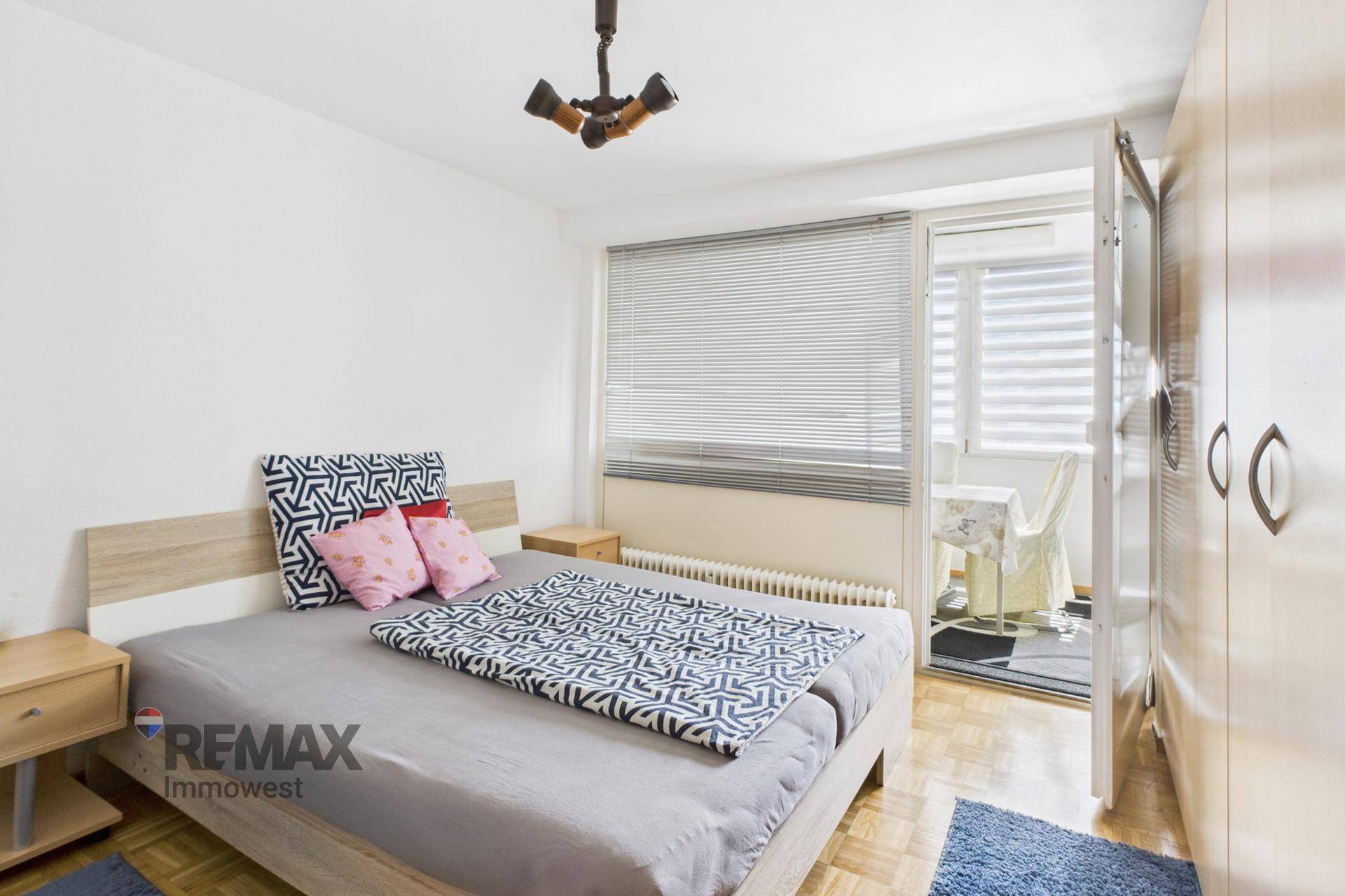 Schlafzimmer mit Doppelbett, Kleiderschrank und Zugang zu einem kleinen Balkon.