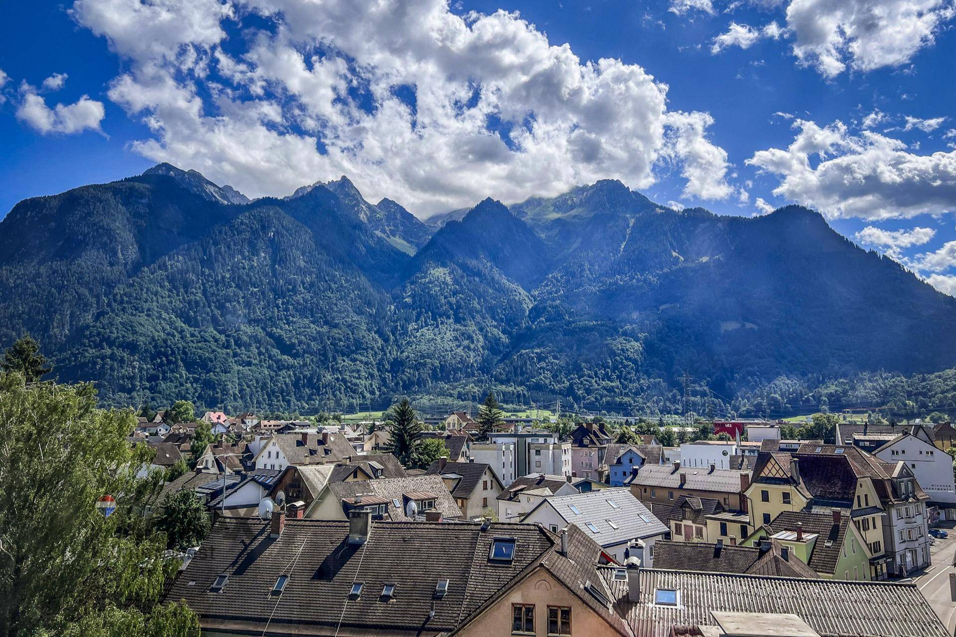 Panoramablick auf eine malerische Stadt im Tal, umgeben von majestätischen Bergen.