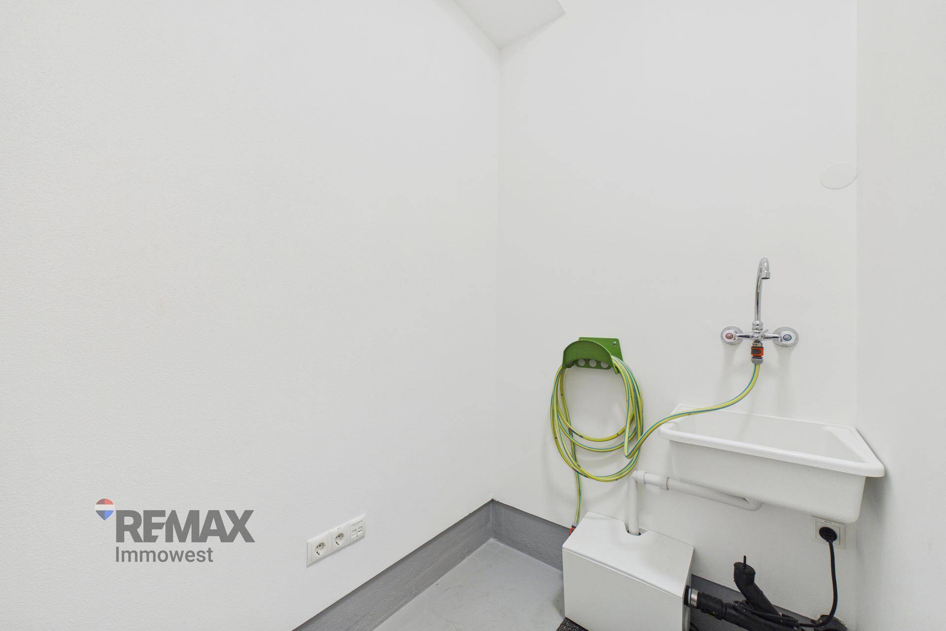 Funktionaler Hauswirtschaftsraum mit Waschbecken, Schlauchanschluss und weißen Wänden.