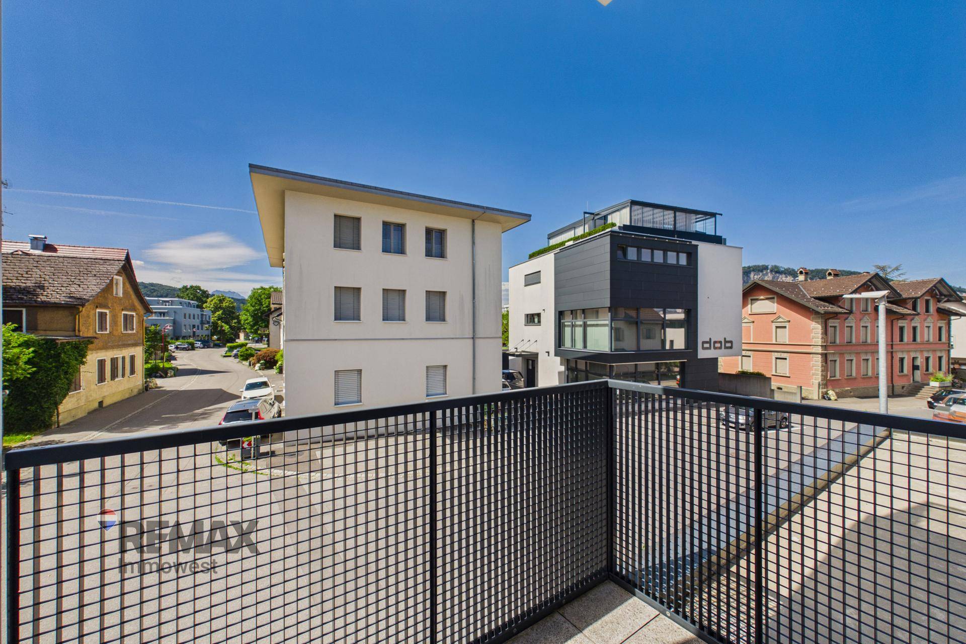 Balkon mit Metallgeländer und Blick auf die umliegenden Gebäude und die Straße.