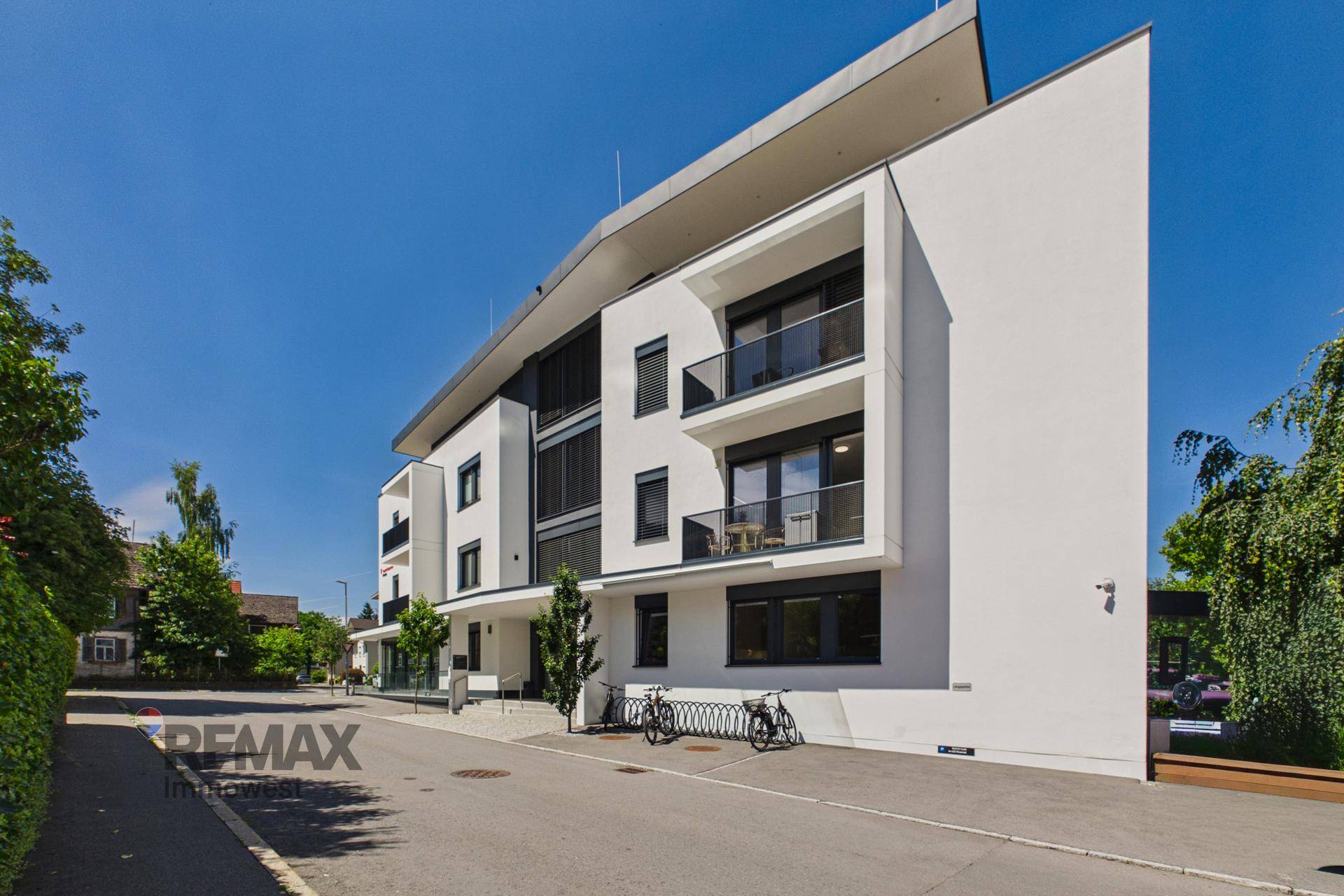 Seitenansicht eines modernen Gebäudes mit klaren Linien, großen Fenstern und Balkonen.