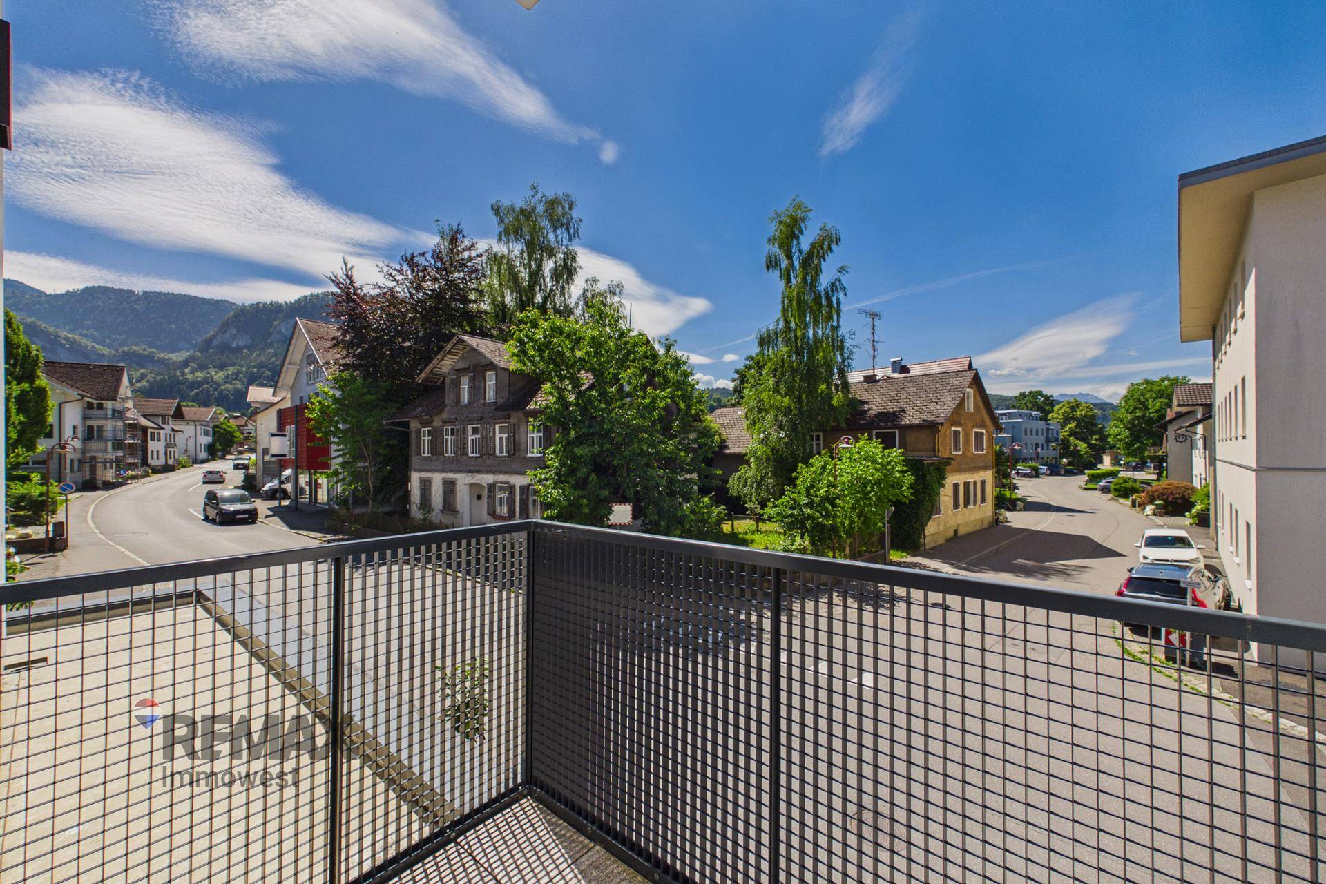 Balkon mit Metallgeländer und weitem Blick auf die umliegende Landschaft und die Berge.