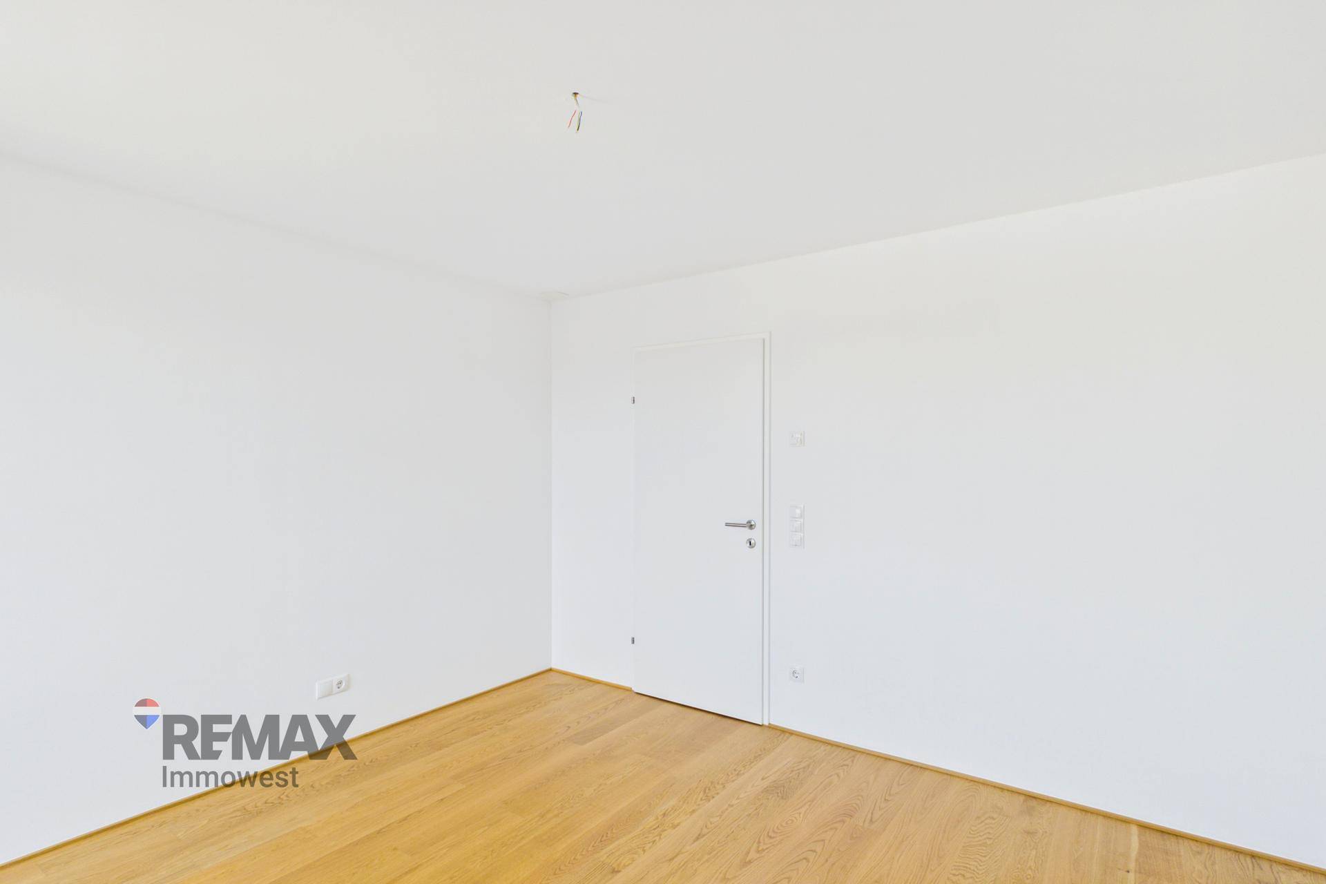 Leerer Raum mit weiß gestrichenen Wänden und hellem Parkettboden, ideal für individuelle Nutzung.