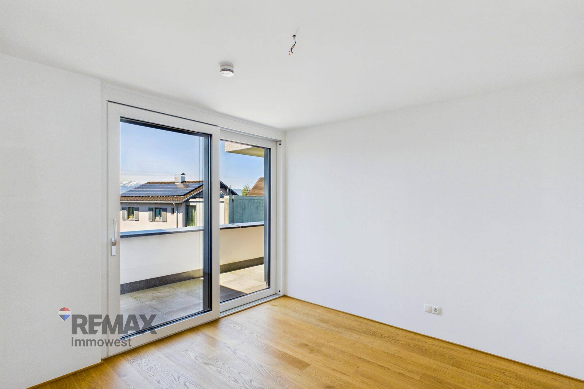 Schlafzimmer mit Parkettboden und direktem Zugang zu einem Balkon, bietet einen weiten Ausblick.