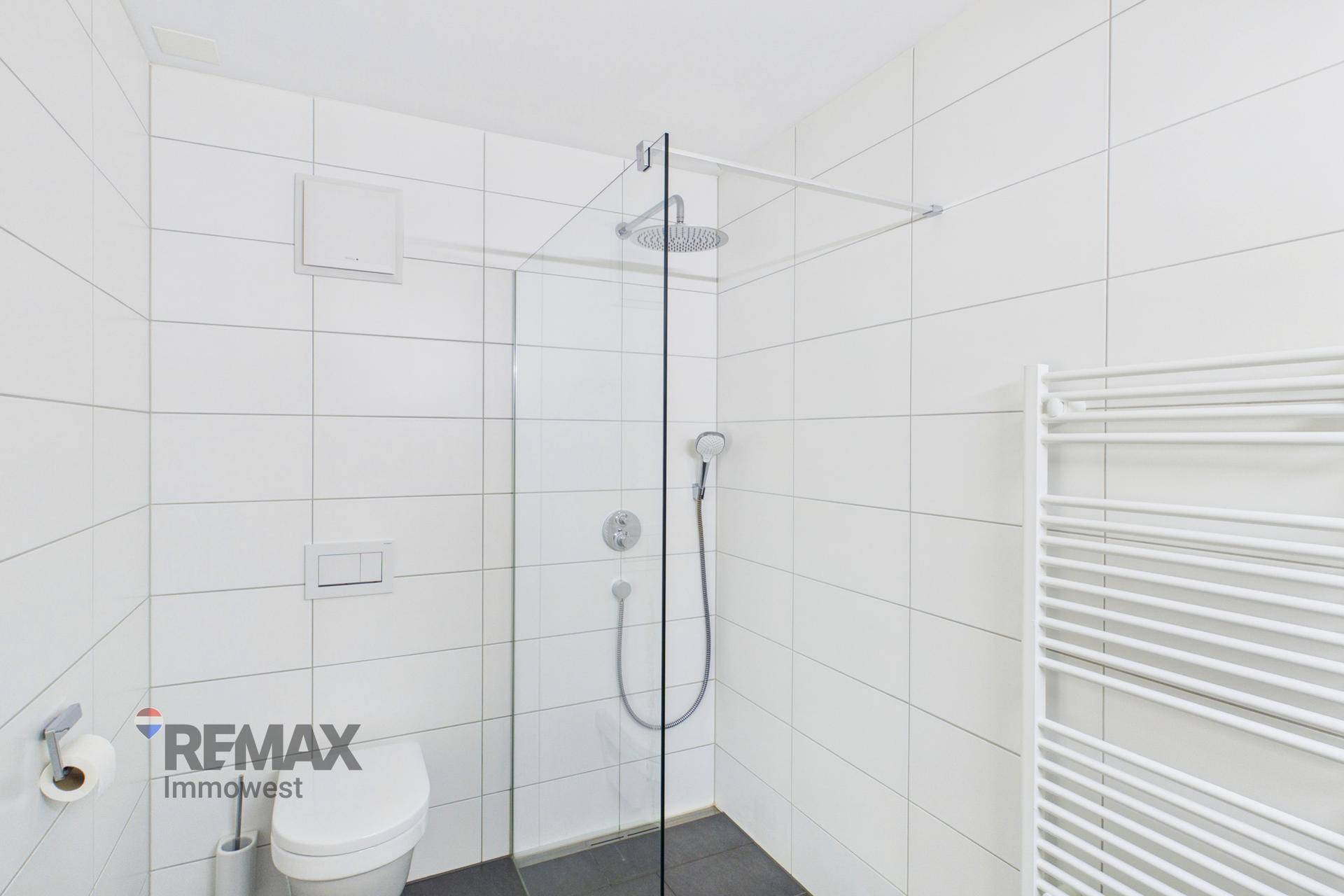 Modernes Badezimmer mit ebenerdiger Dusche, Wand-WC und weißen Fliesen.