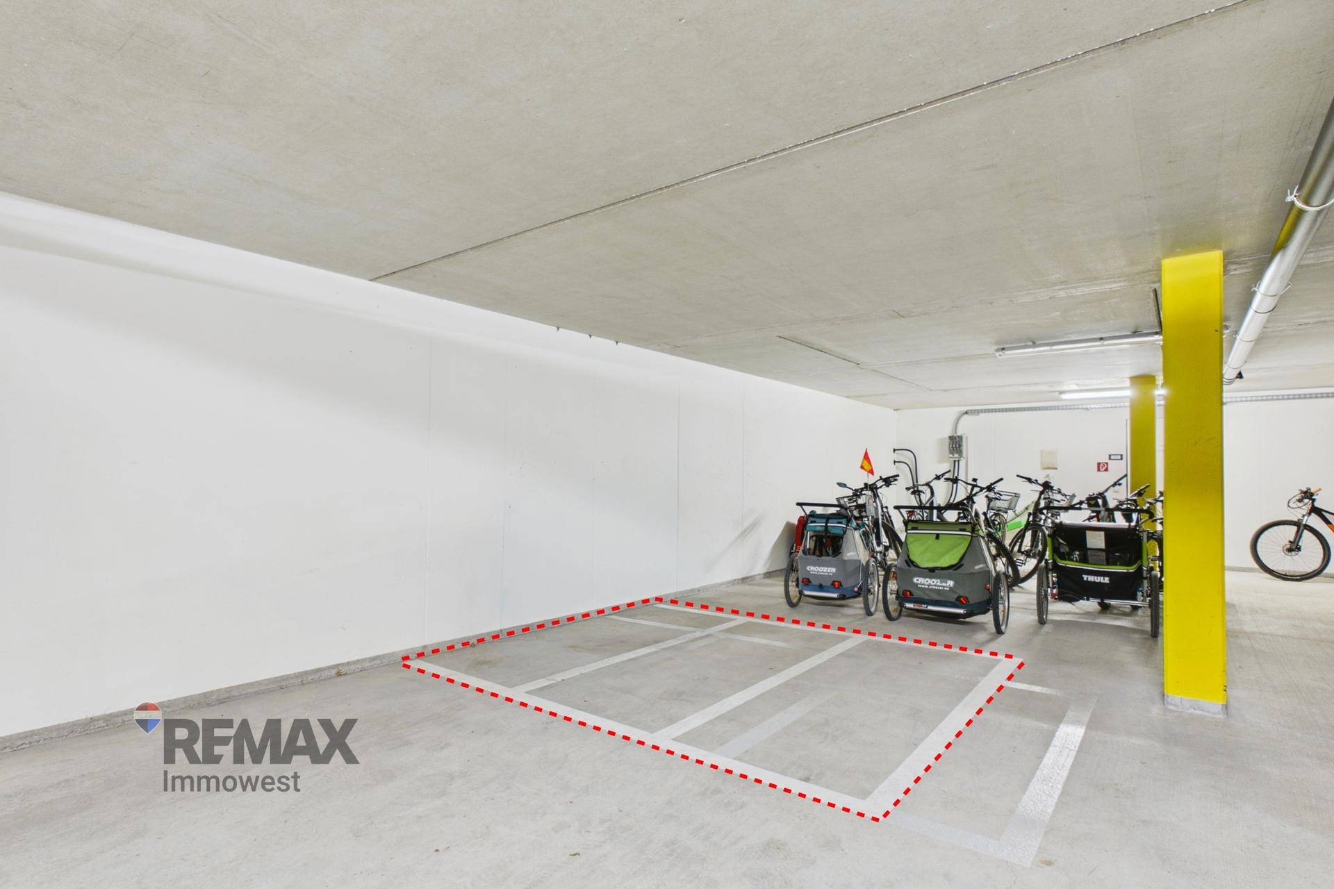 Tiefgaragenstellplatz mit Fahrrädern und markierter Parkfläche in einem modernen Gebäude.