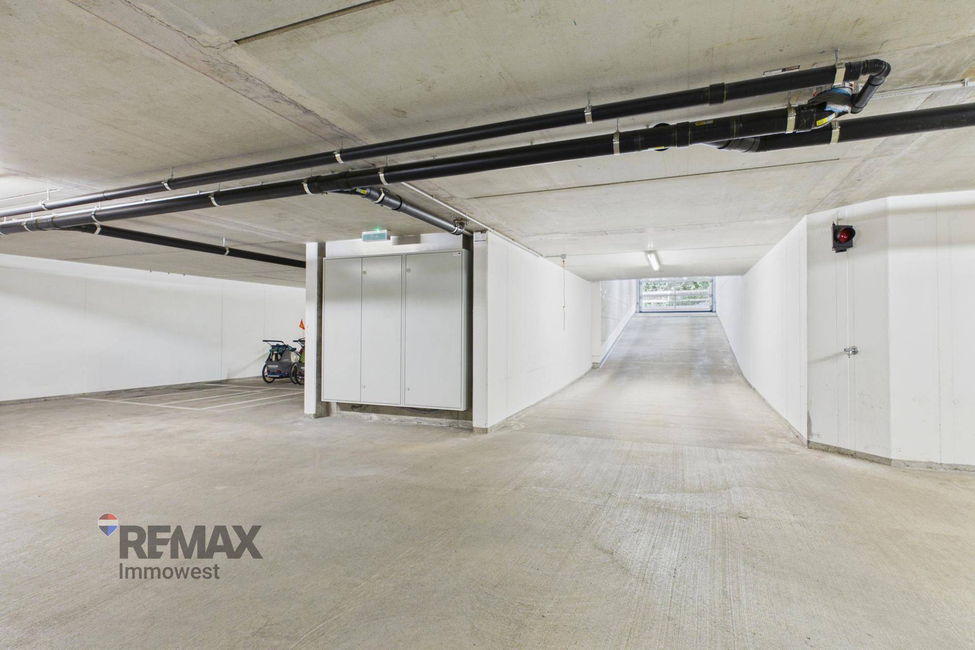 Einfahrt zur Tiefgarage mit Rampe und Schließfächern in einem modernen Wohngebäude.