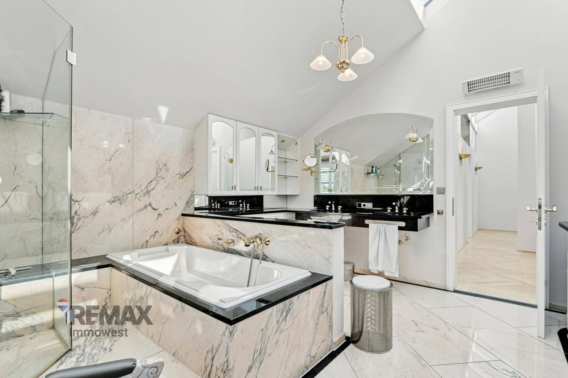 Luxuriöses Badezimmer mit Marmorfliesen, eingebauter Badewanne und separater Dusche unter der Dachschräge.