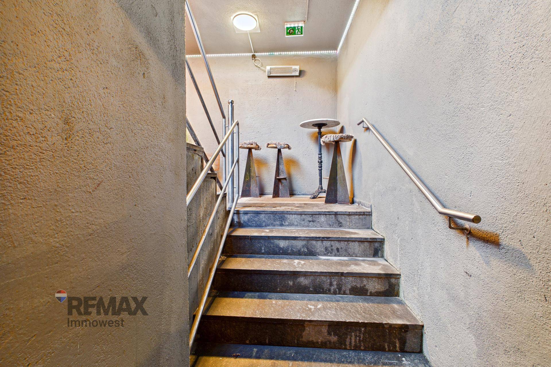 Schlichtes Treppenhaus mit Betontreppen und Metallgeländer, das nach oben führt.
