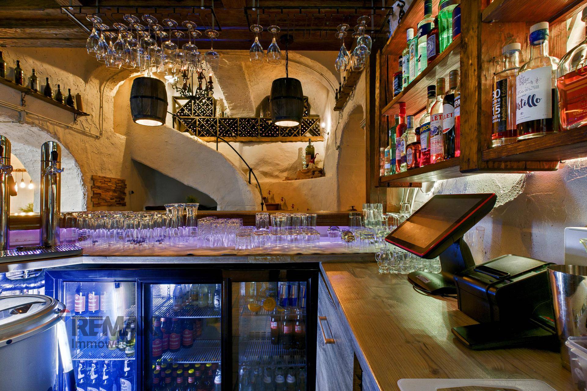 Thekenbereich der Bar mit zahlreichen Gläsern, Flaschen und einem Kassensystem.