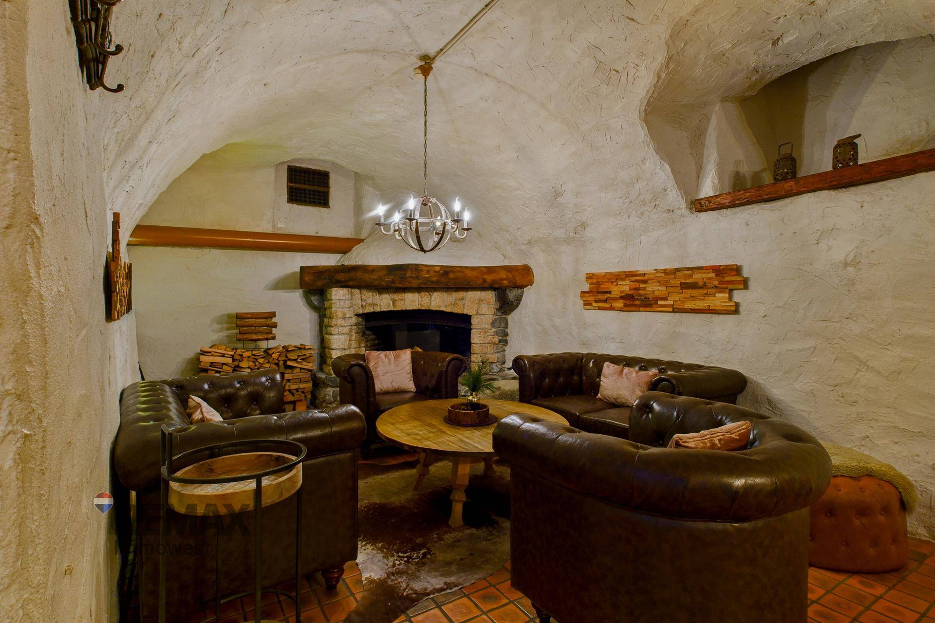 Rustikaler Loungebereich mit Ledersofas, einem Holztisch und einem traditionellen Steinkamin.