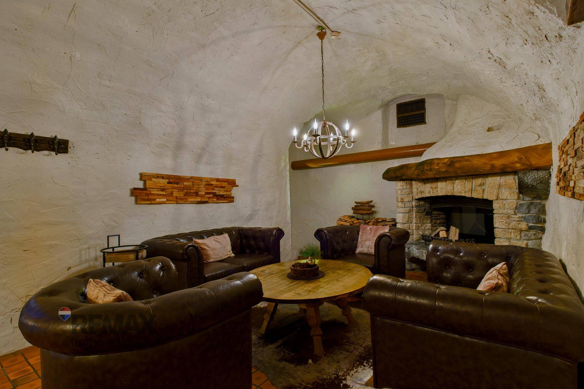 Gemütlicher Loungebereich mit Ledersofas, einem runden Holztisch und einem großen Kamin.