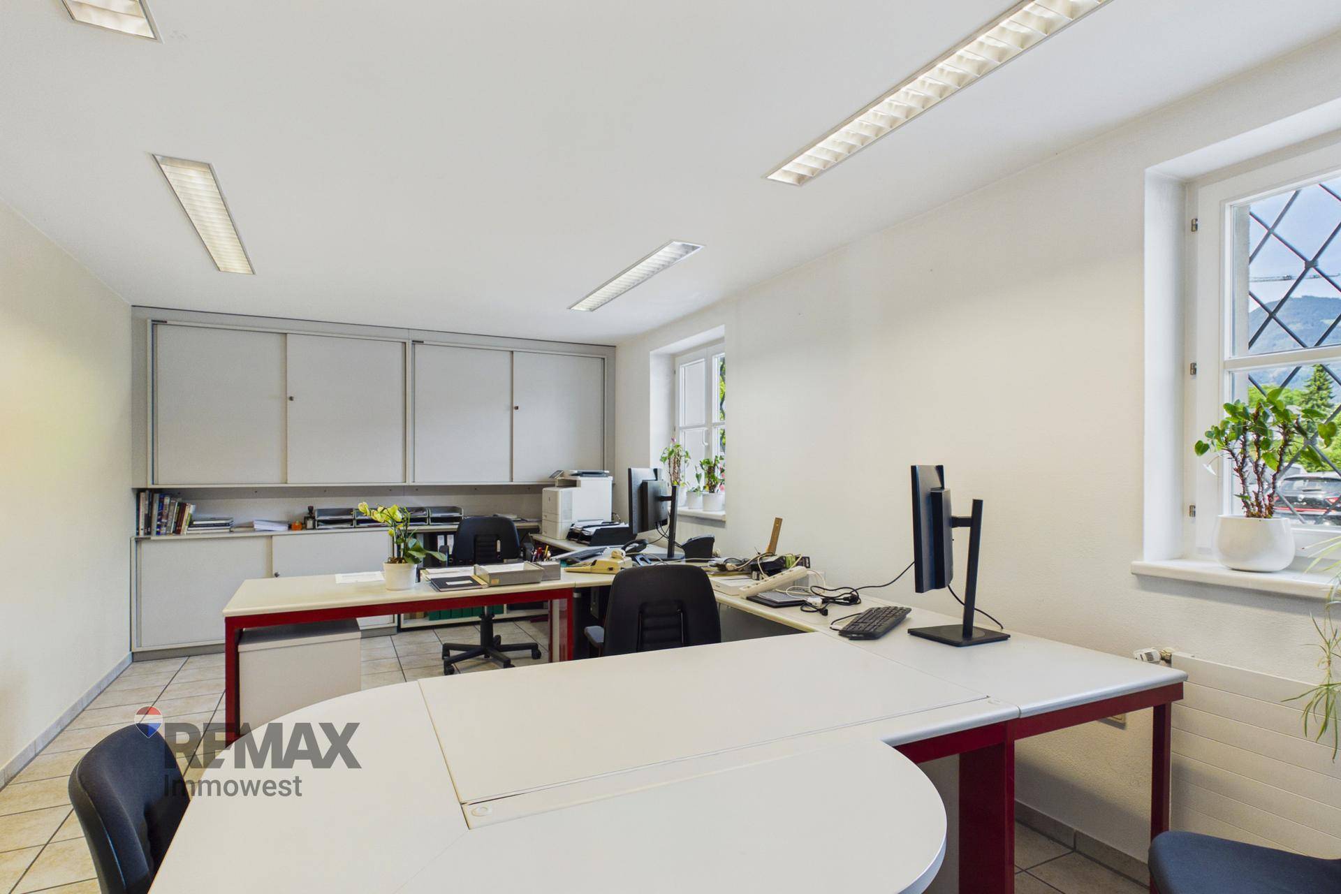 Helles Büro mit mehreren Arbeitsplätzen, großen Fenstern und praktischen Einbauschränken.