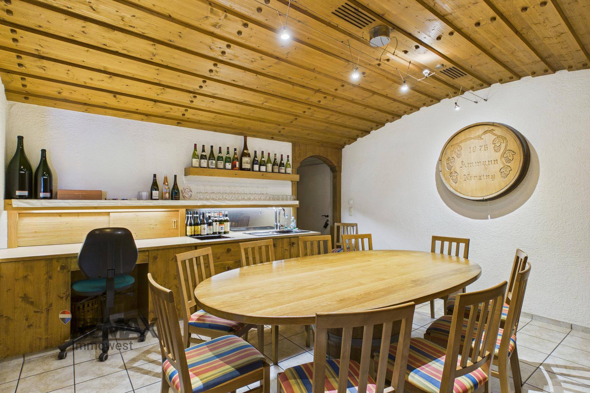 Gemütlicher Essbereich mit Holztisch, bunten Stühlen und einer Holzdecke, ideal für Weinproben.