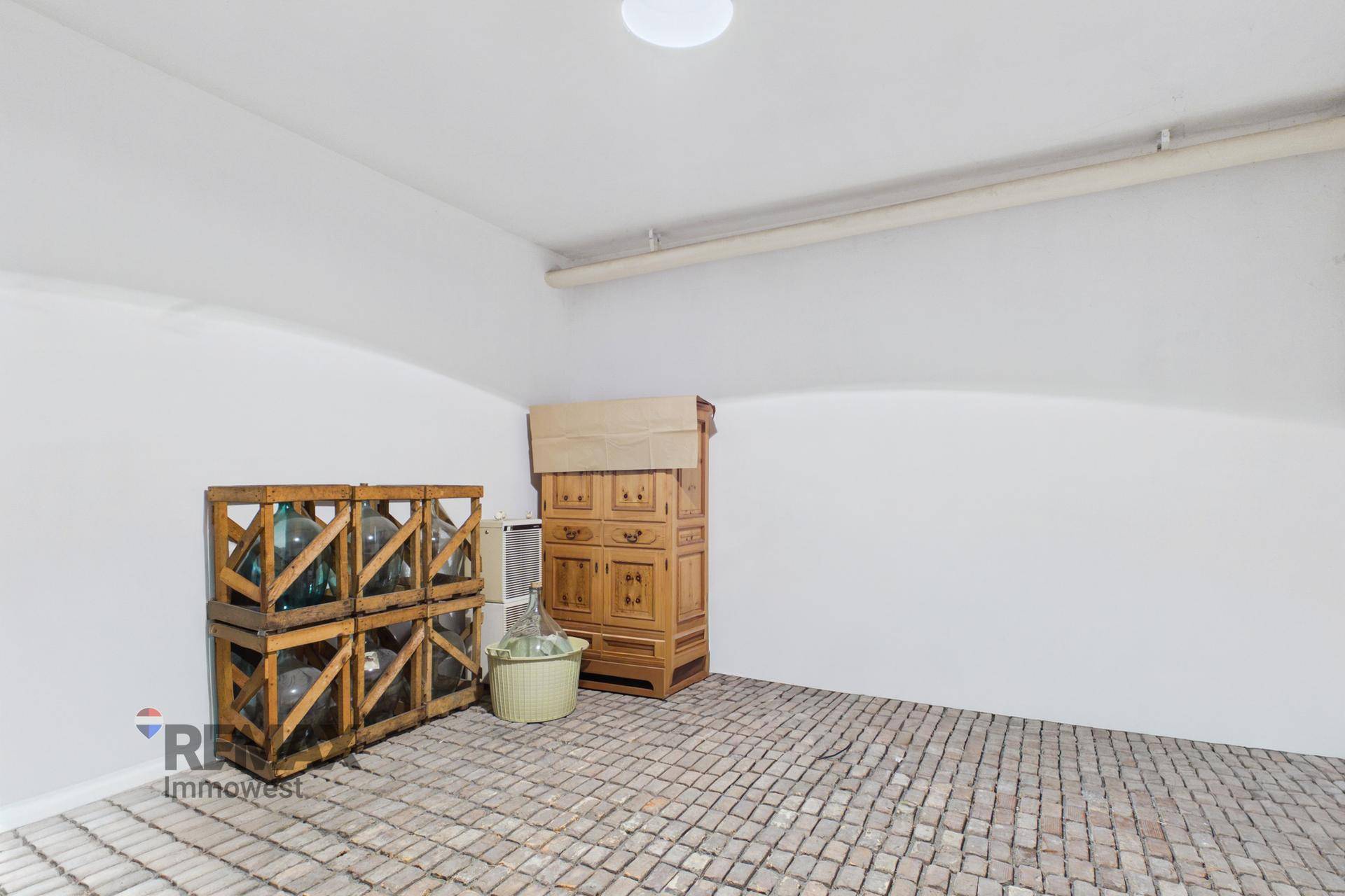 Dachbodenraum mit schräger Decke, Ziegelboden und gelagerten Gegenständen, ideal als Abstellfläche.