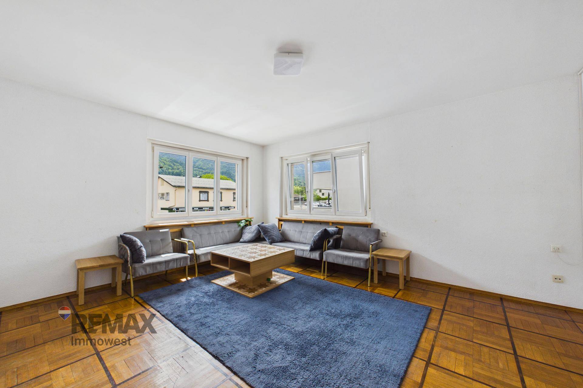 Geräumiges Wohnzimmer mit Fischgrätparkett, bequemen Sofas und Blick auf die umliegende Landschaft.