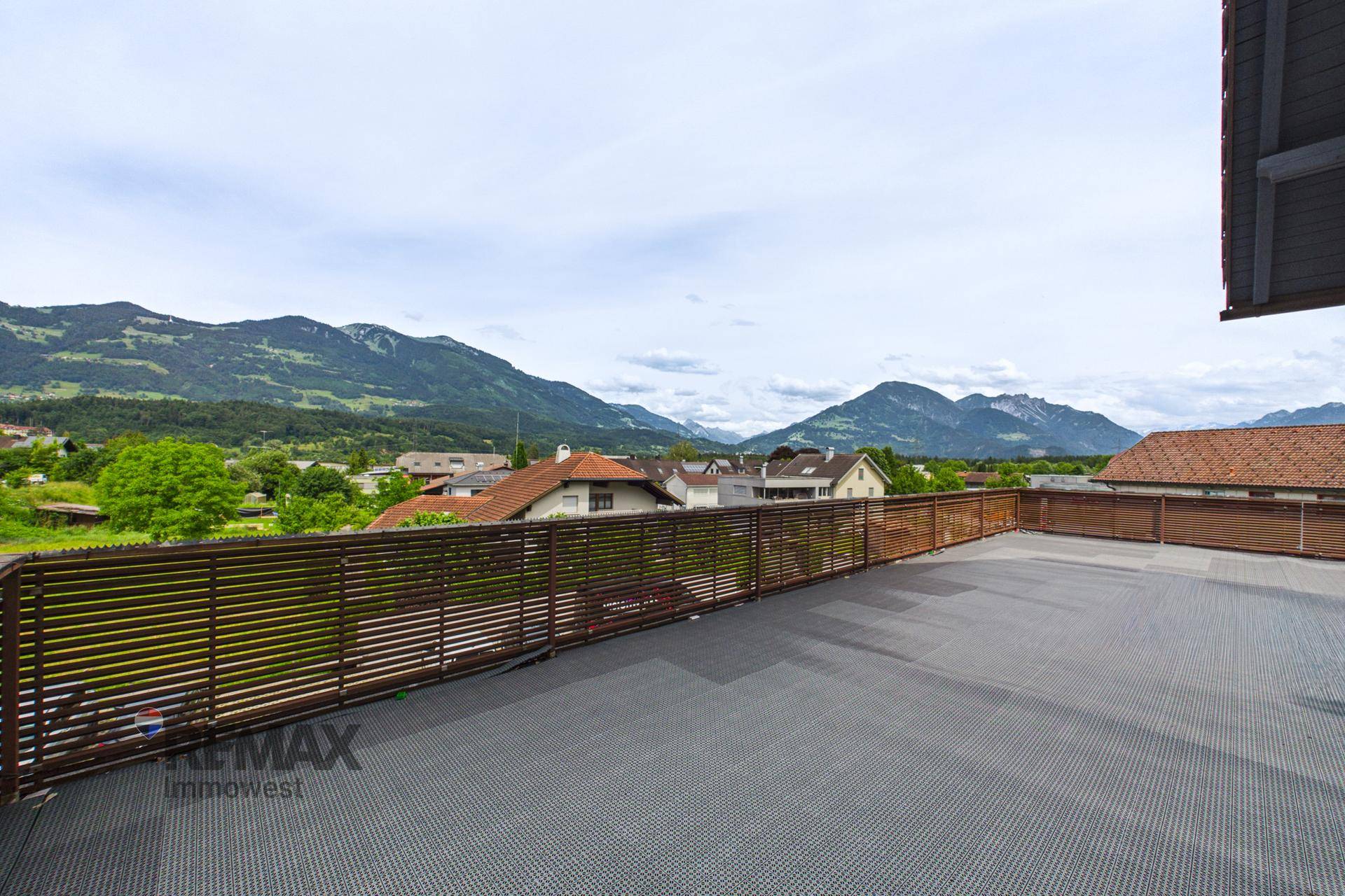 Geräumige Außenterrasse mit Holzzaun und weitem Blick auf die Berglandschaft.