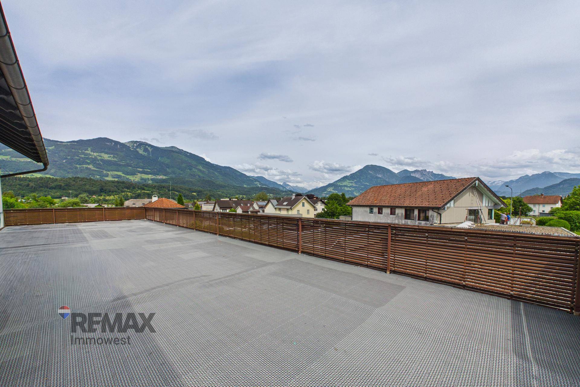 Große Terrasse mit Panoramablick auf die Alpen und die umliegende Siedlung.