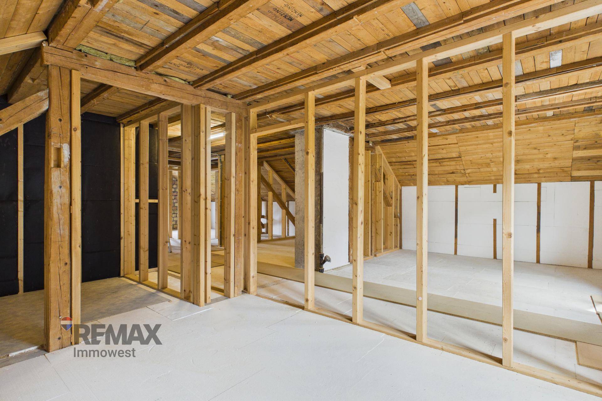 Dachgeschoss im Rohbau mit sichtbaren Holzbalken und Dachschrägen.
