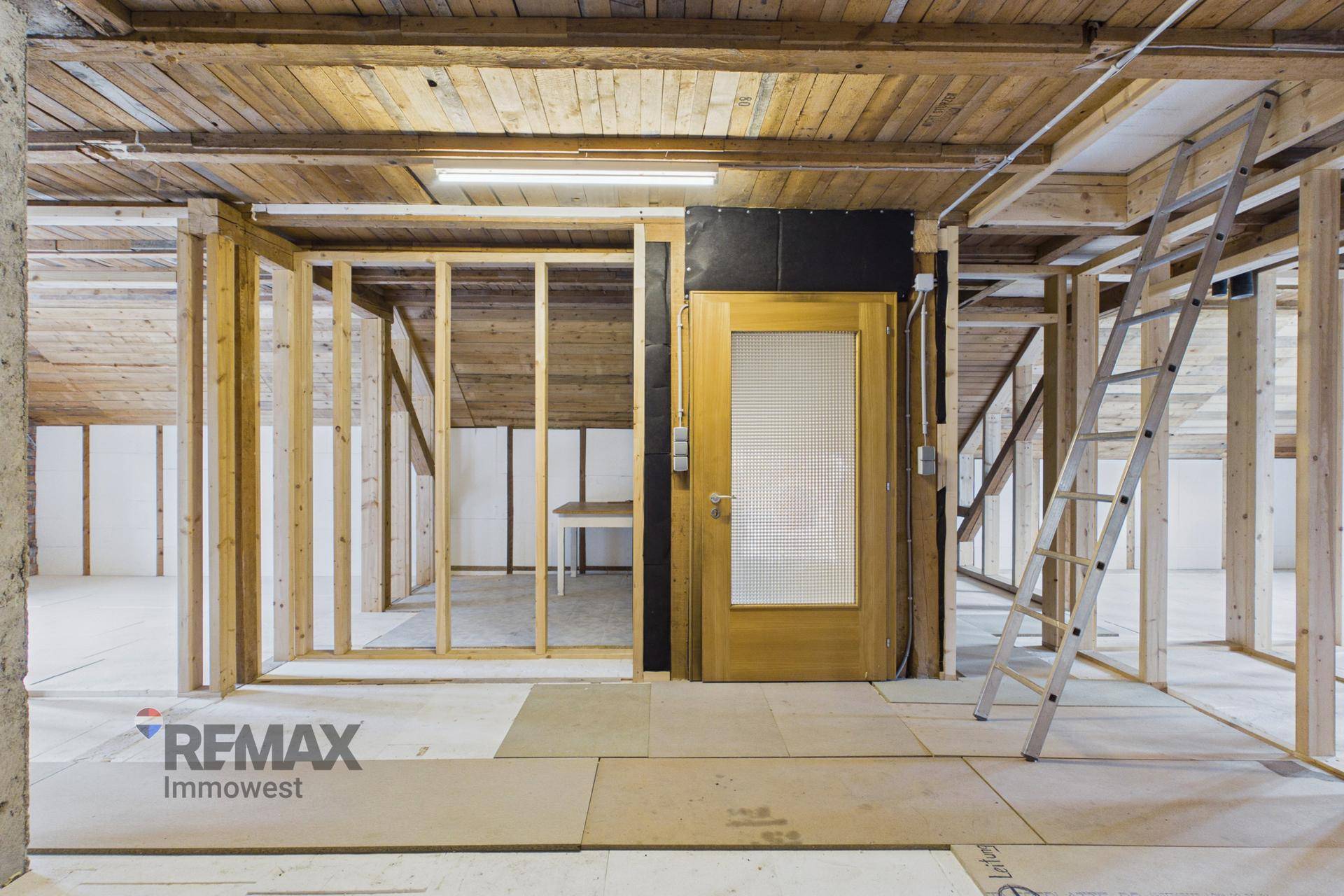 Dachgeschoss im Rohbau mit Holzkonstruktion und einer Aufzugstür.
