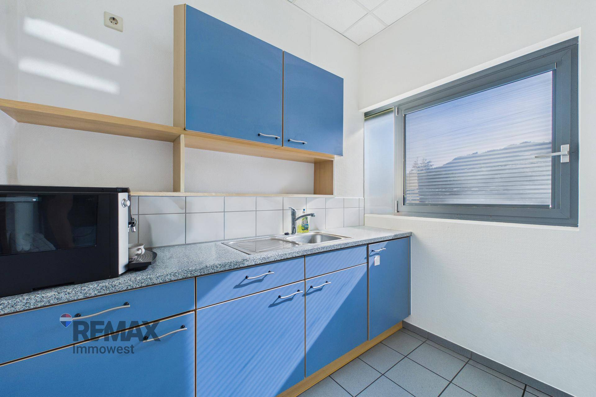 Kleine Küchenzeile mit blauen Schränken, Granitarbeitsplatte, Spüle und Mikrowelle.