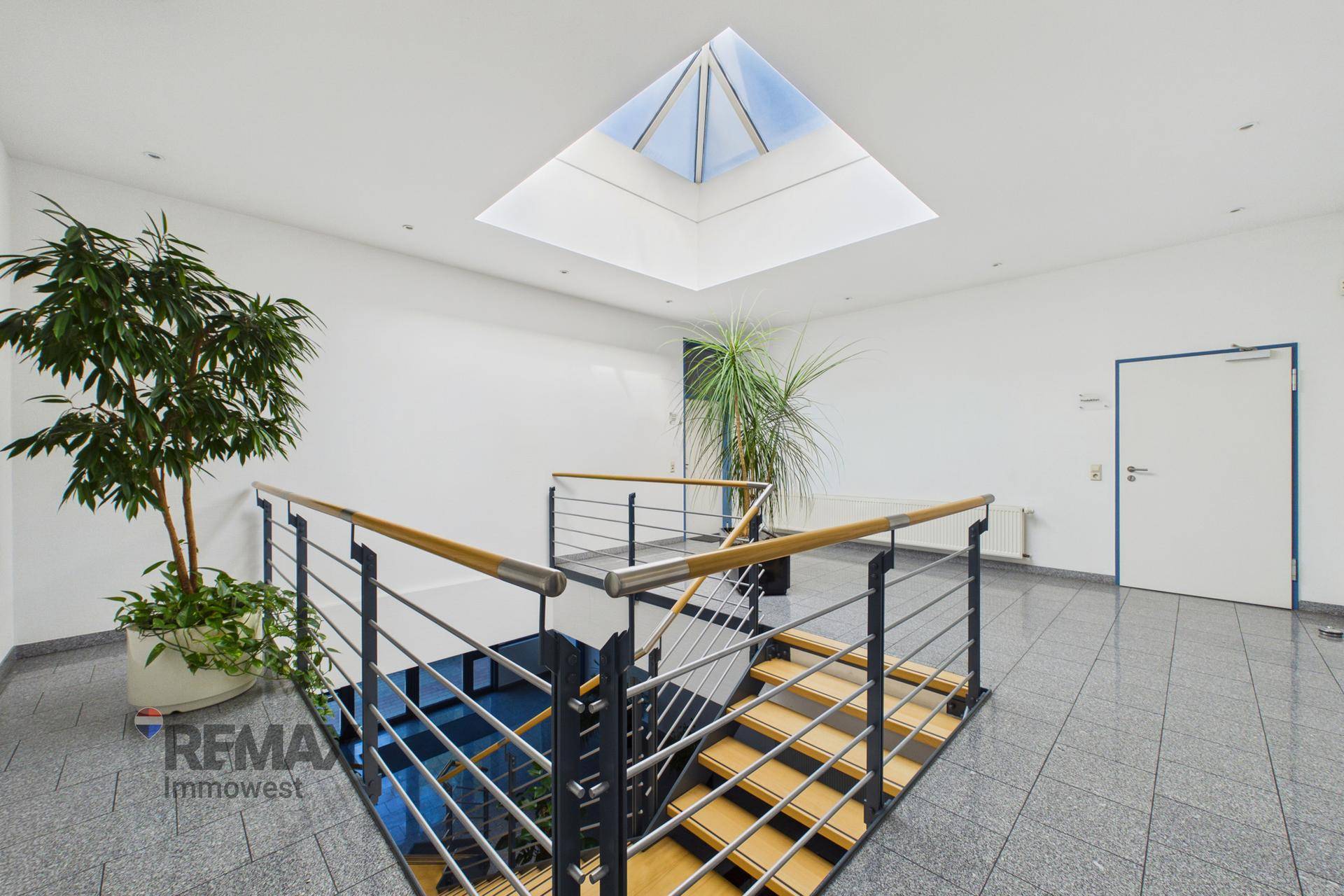 Treppenhaus mit Oberlicht, das viel natürliches Licht hereinlässt, und modernen Geländern.