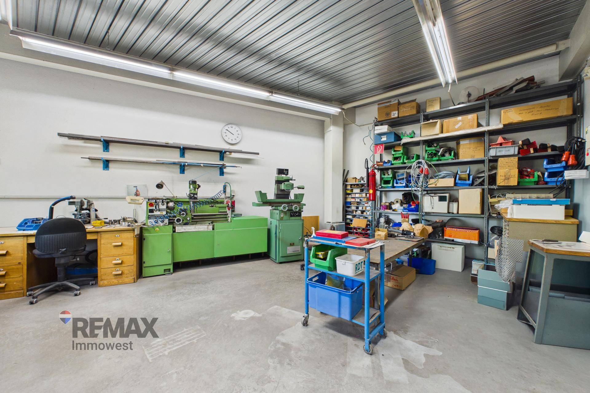 Werkstatt mit verschiedenen Werkbänken, Maschinen und Regalen voller Werkzeuge und Materialien.