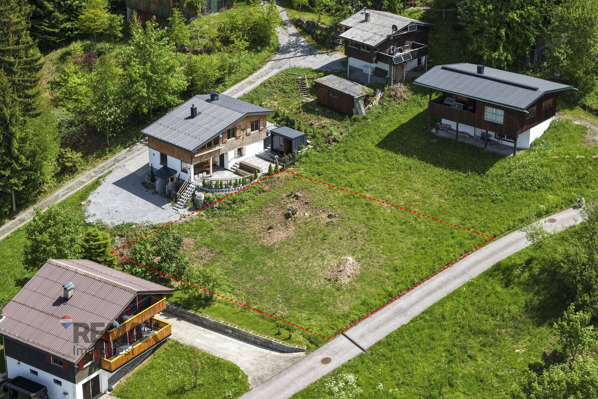Luftaufnahme eines umgrenzten Baugrundstücks, umgeben von Wohnhäusern und grünen Wiesen.