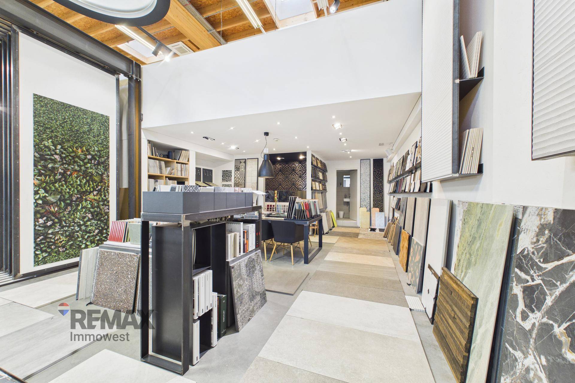 Moderner Showroom-Bereich mit einer grünen Pflanzenwand und einer Vielzahl von Fliesenmustern für Inspiration.