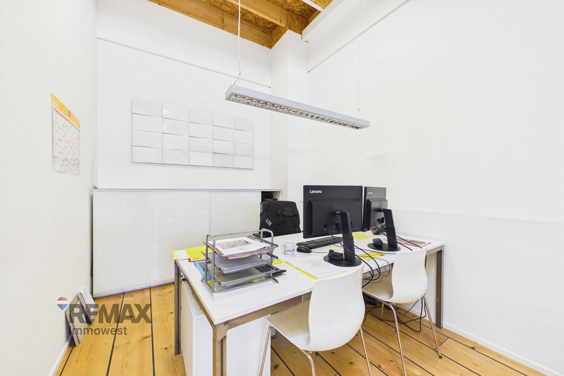Kleineres, helles Büro mit einem Arbeitsplatz, weißen Möbeln und Holzboden.