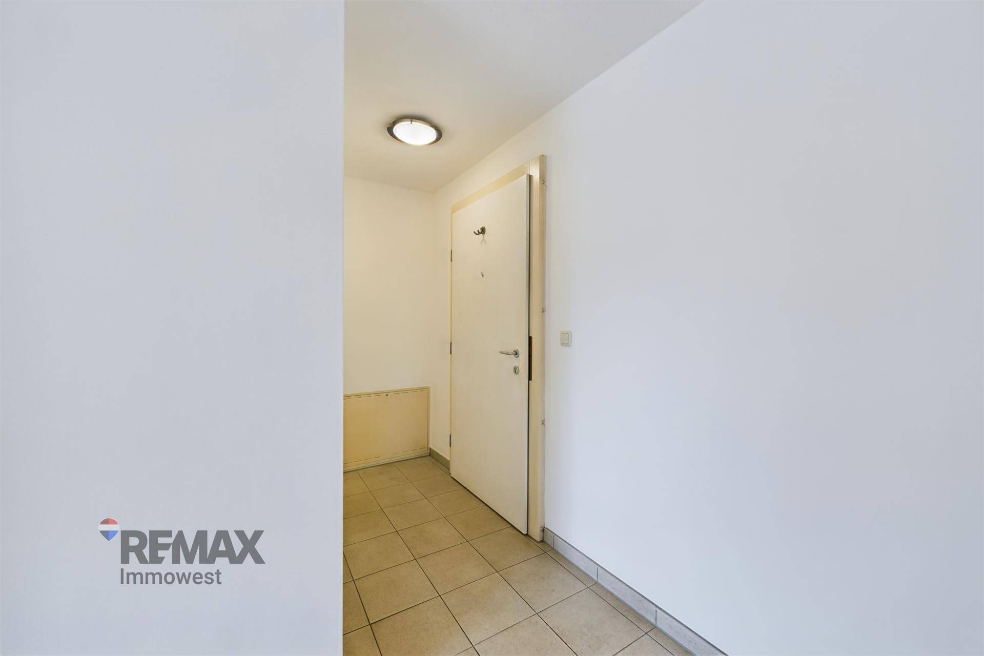 Eingangsbereich mit Fliesenboden und weißer Eingangstür, die in die Wohnung führt.