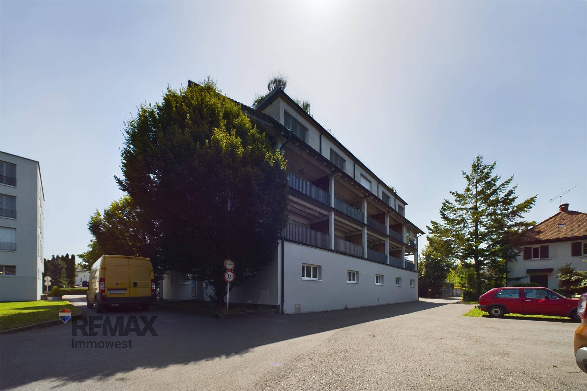 Mehrfamilienhaus mit Balkonen und Bäumen in einer ruhigen Wohngegend.