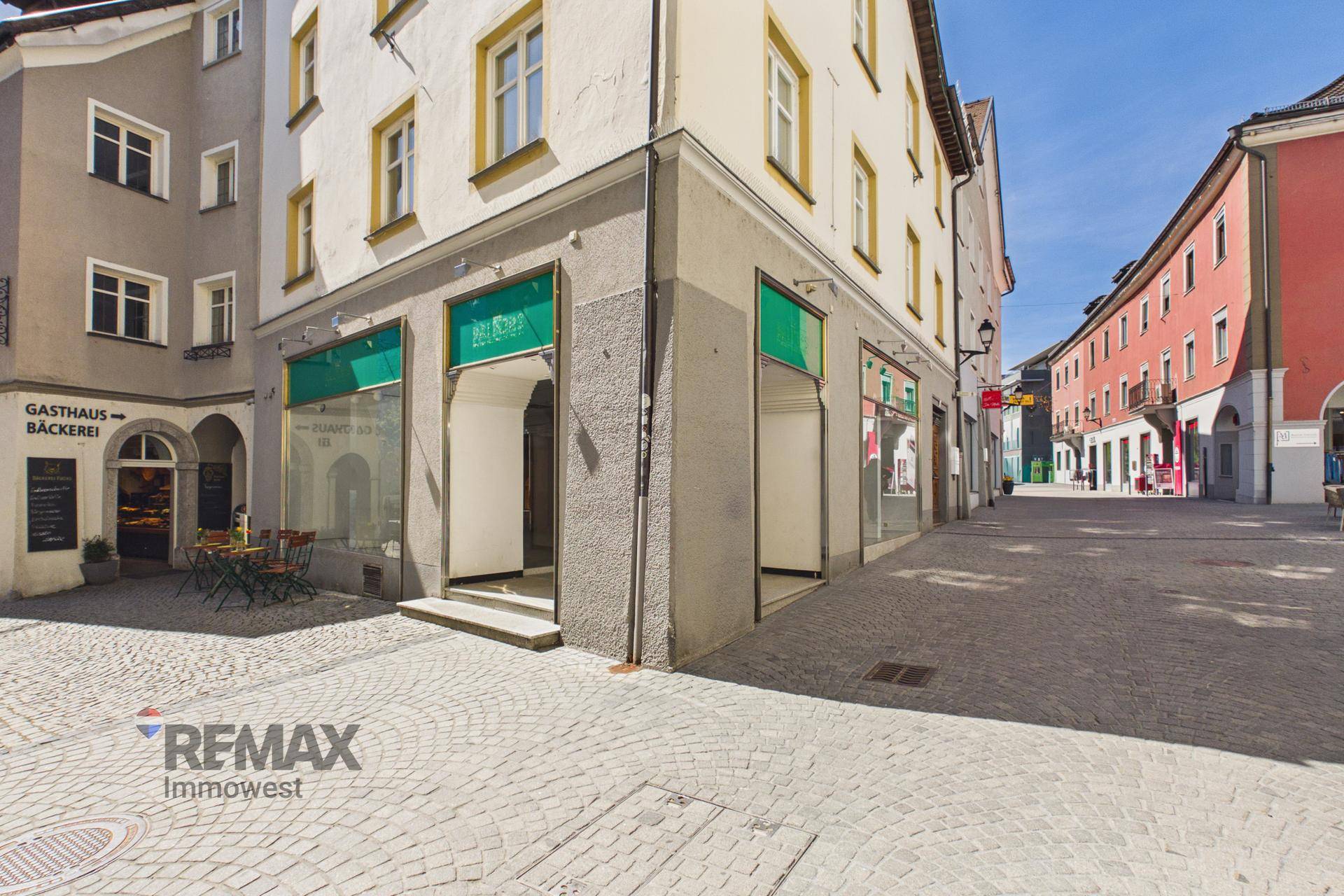 Nahaufnahme des historischen Gebäudes mit Schaufenstern im Erdgeschoss und einem Gasthaus in der Gasse.