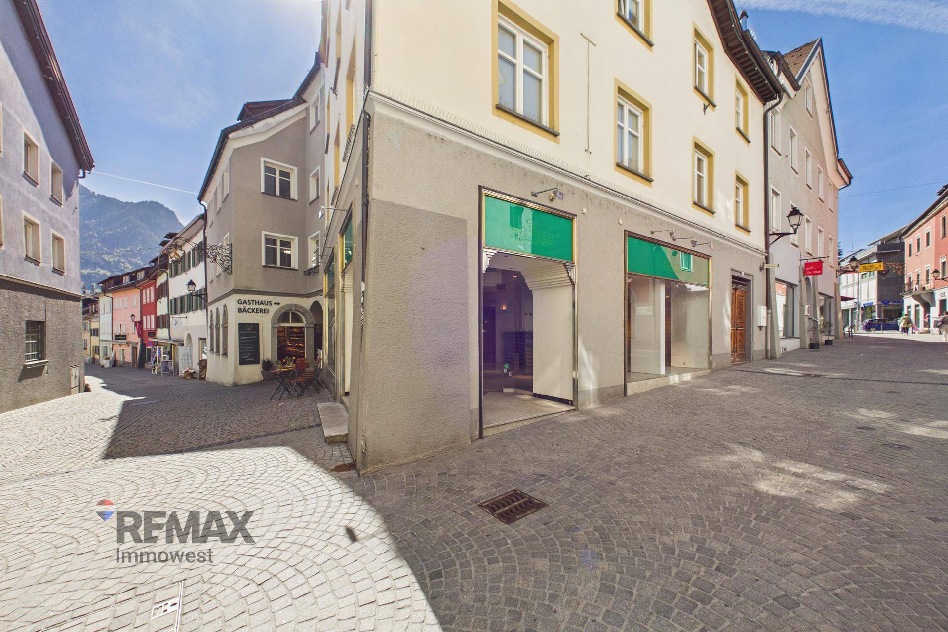 Malerische Gasse mit historischen Gebäuden und einem Blick auf die umliegenden Berge im Hintergrund.