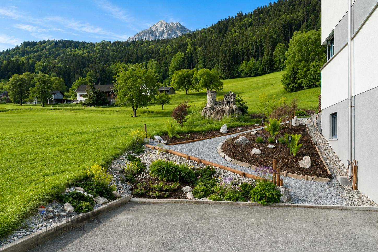 Kreativ gestalteter Gartenbereich mit Kieswegen, Pflanzen und einer kleinen Burgdekoration.