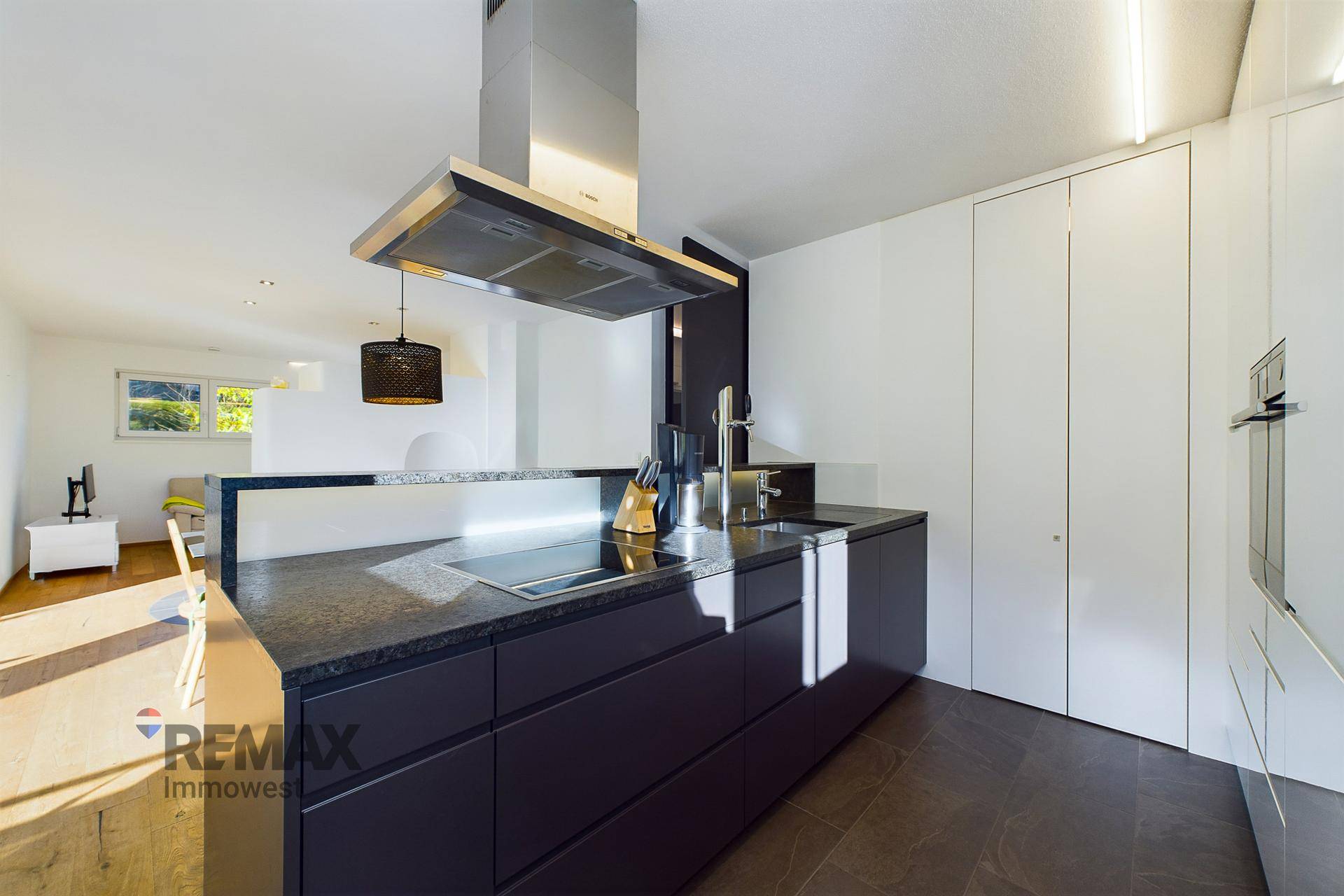 Moderne Küche mit dunklen Schränken, Granitarbeitsplatte und integriertem Induktionskochfeld.
