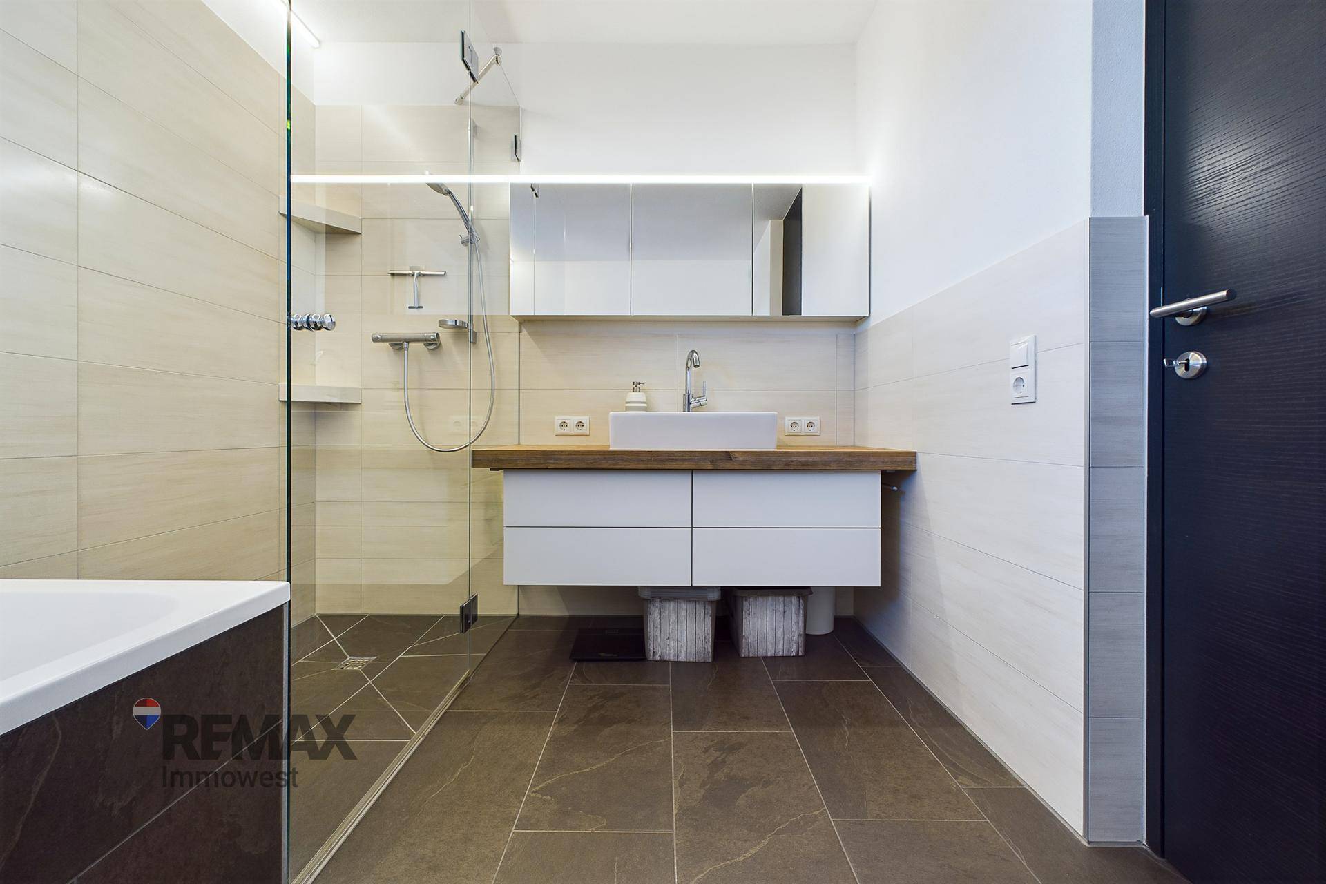 Modernes Badezimmer mit begehbarer Dusche, Waschtisch und Spiegelschrank.