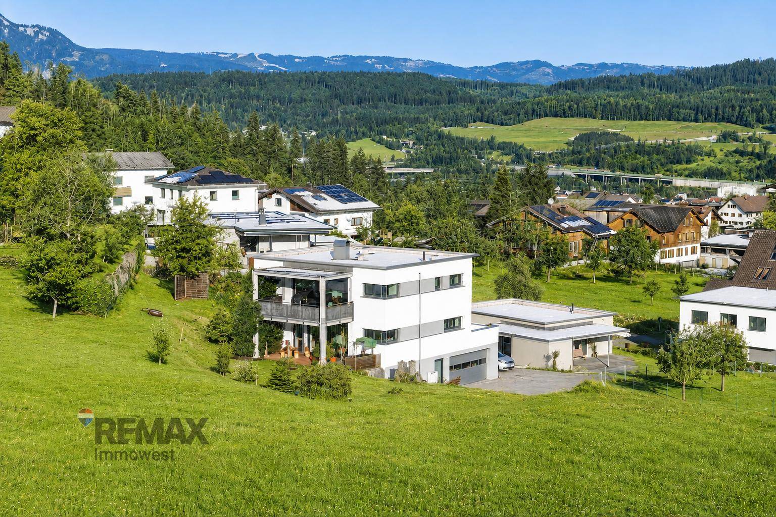 Panoramablick auf das moderne Wohnhaus eingebettet in eine grüne Berglandschaft.