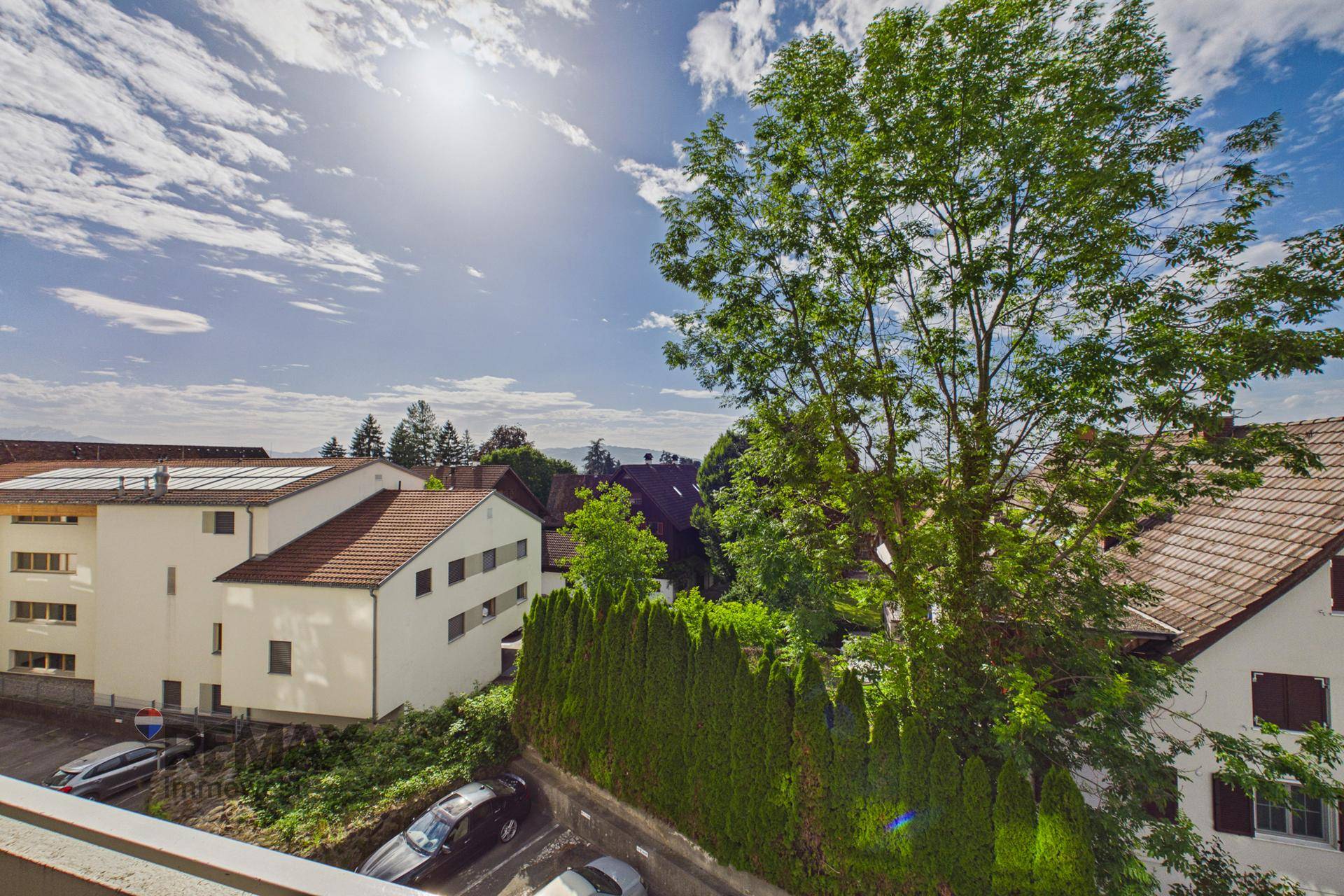 Weitblick über die umliegenden Häuser und grüne Bäume unter blauem Himmel.