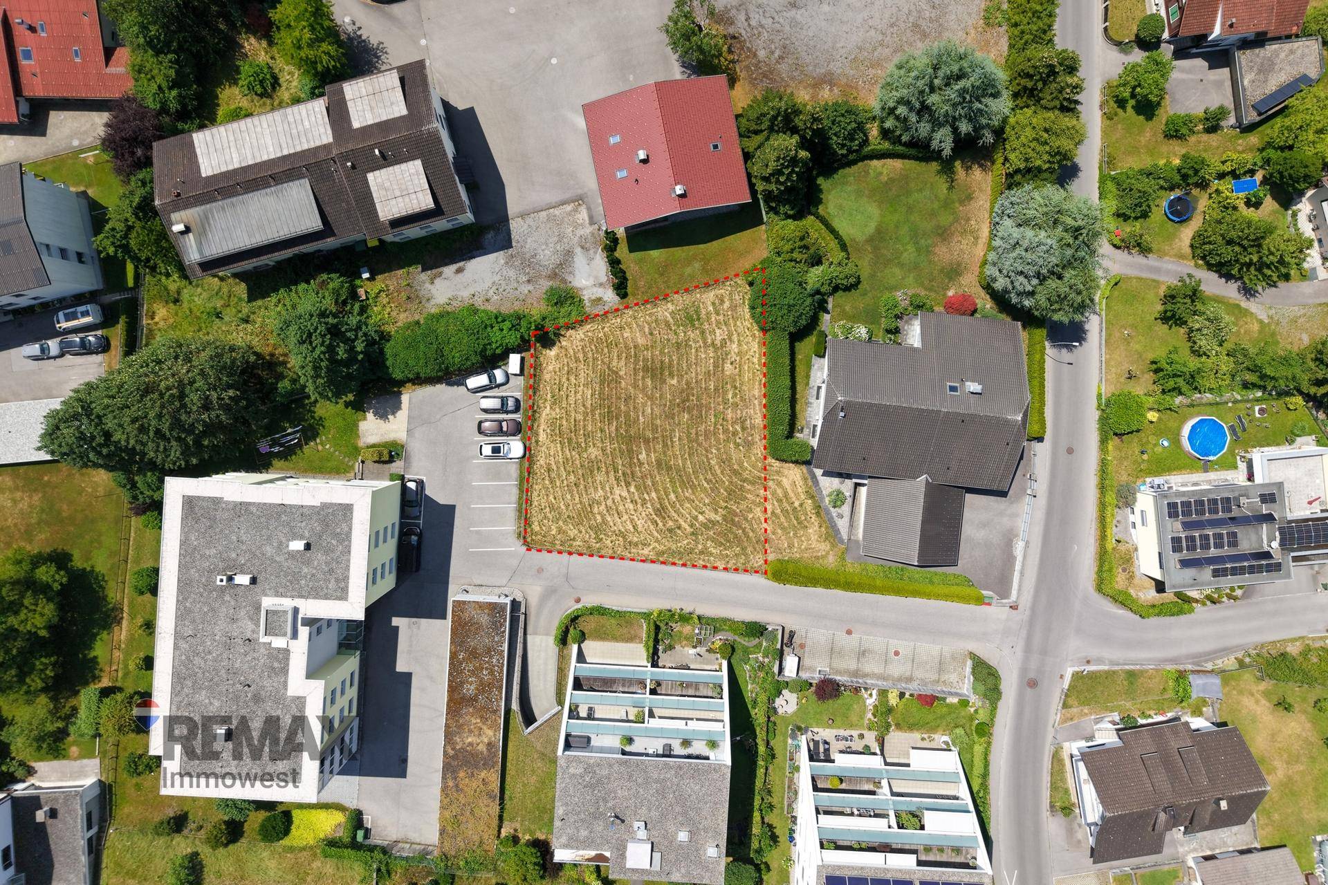 Senkrechte Luftaufnahme des Baugrundstücks mit angrenzenden Parkplätzen und Gebäuden.