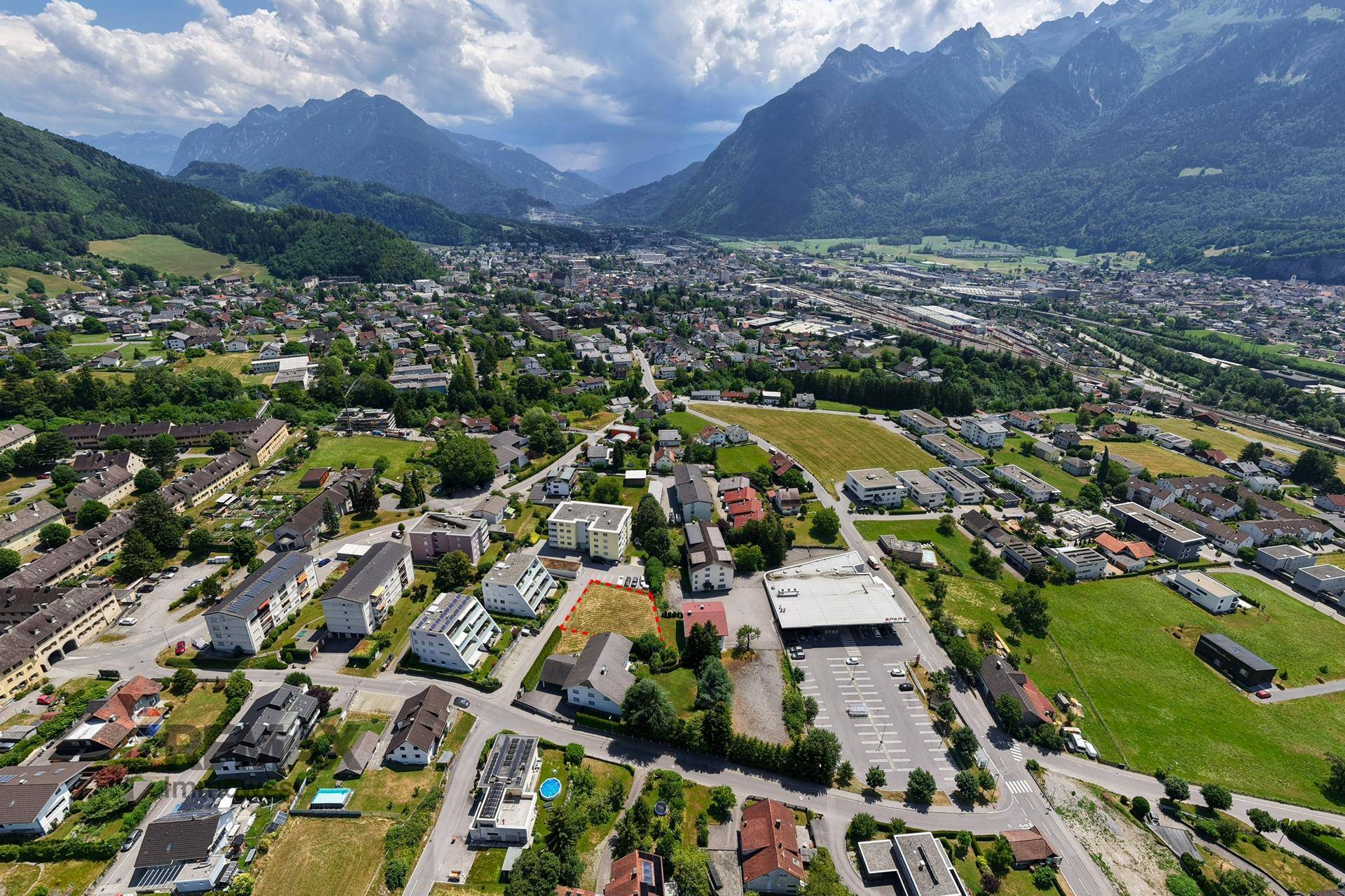 Umfassende Luftaufnahme des Baugrundstücks in einer städtischen Umgebung mit Bergblick.