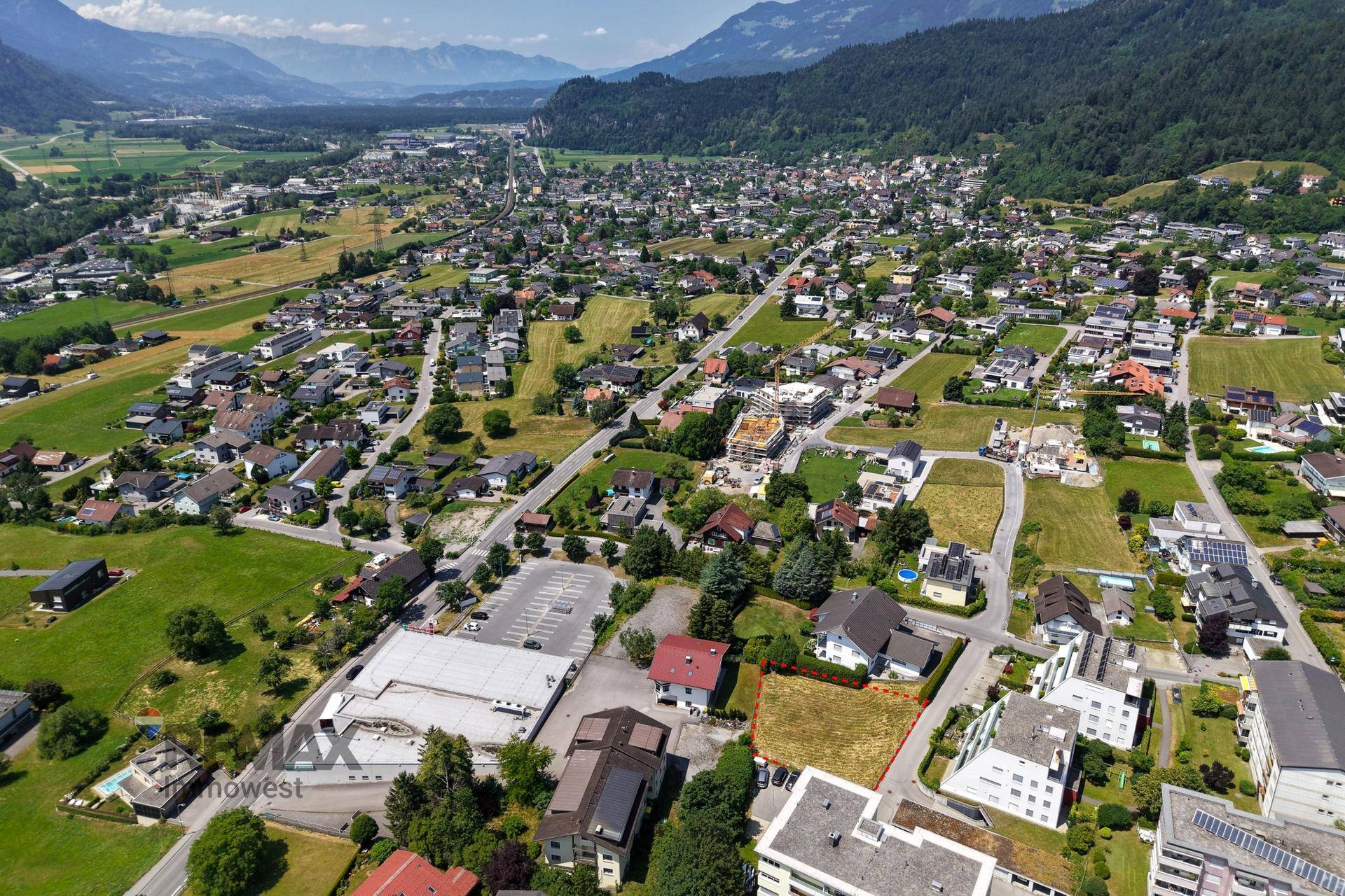 Luftaufnahme des Baugrundstücks in einer Siedlung mit weitem Blick auf die Landschaft.